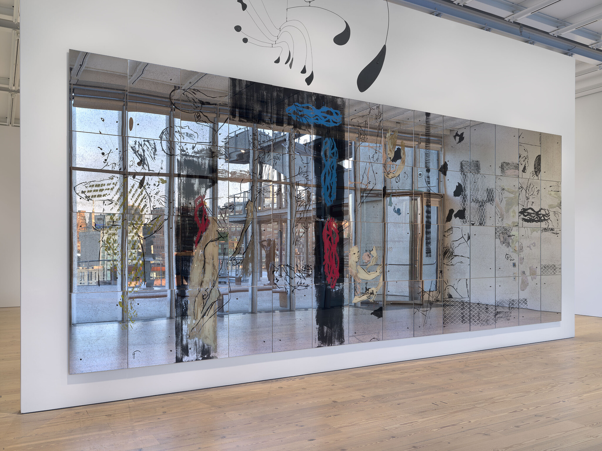 Large mirrored artwork with abstract drawings and colored shapes, reflecting windows and the gallery space around it.