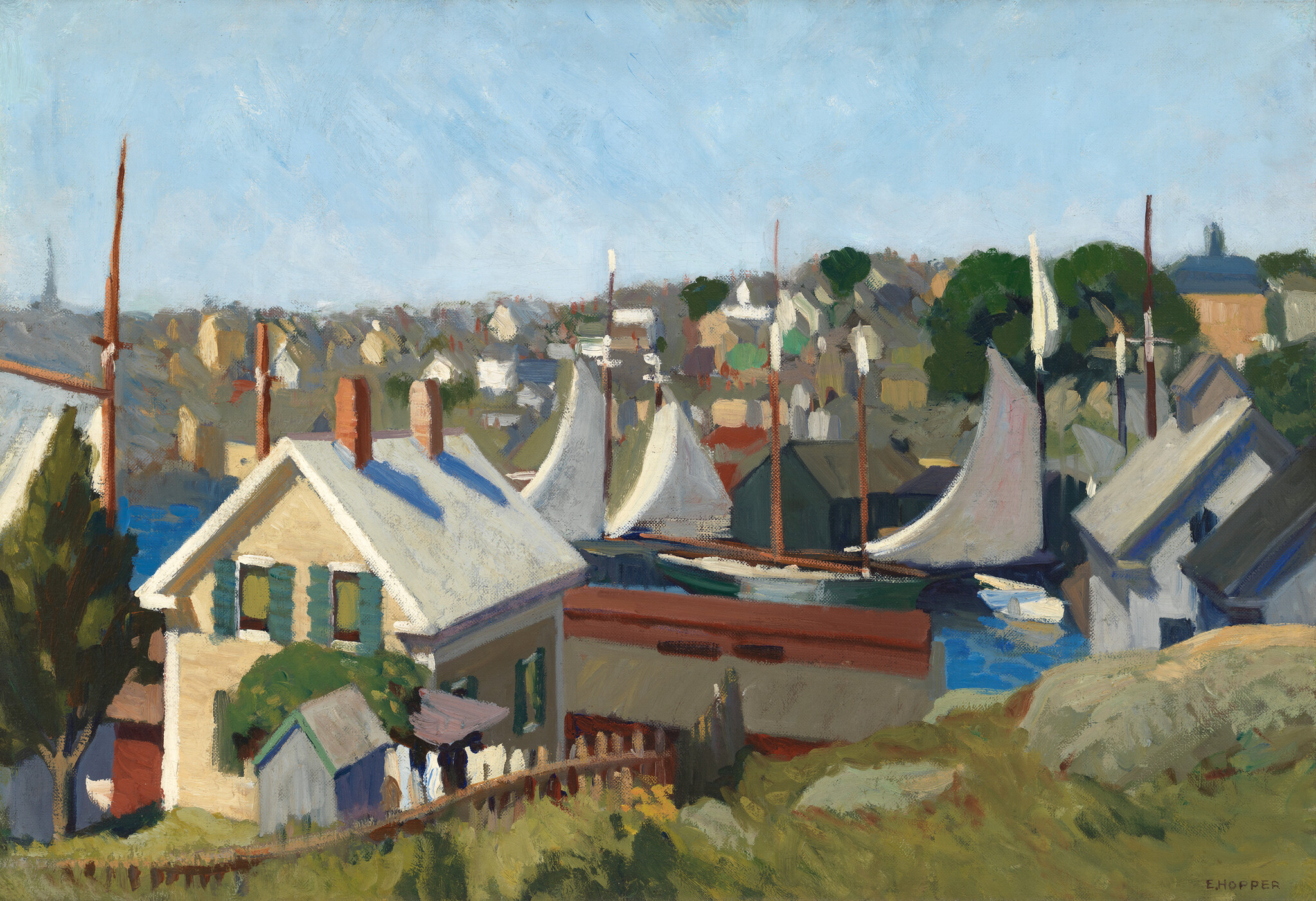 A coastal village with white-sailed boats moored near houses under a clear blue sky.