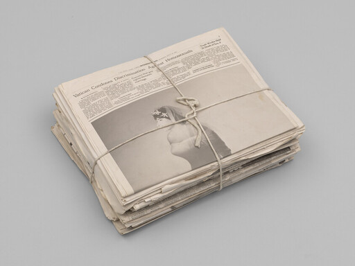 A tied stack of newspapers with a large front-page photo and visible headline about discrimination.