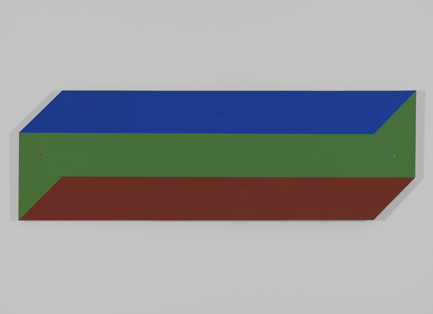 A long rectangular three-colored wall sculpture with blue top, green middle, and red bottom.