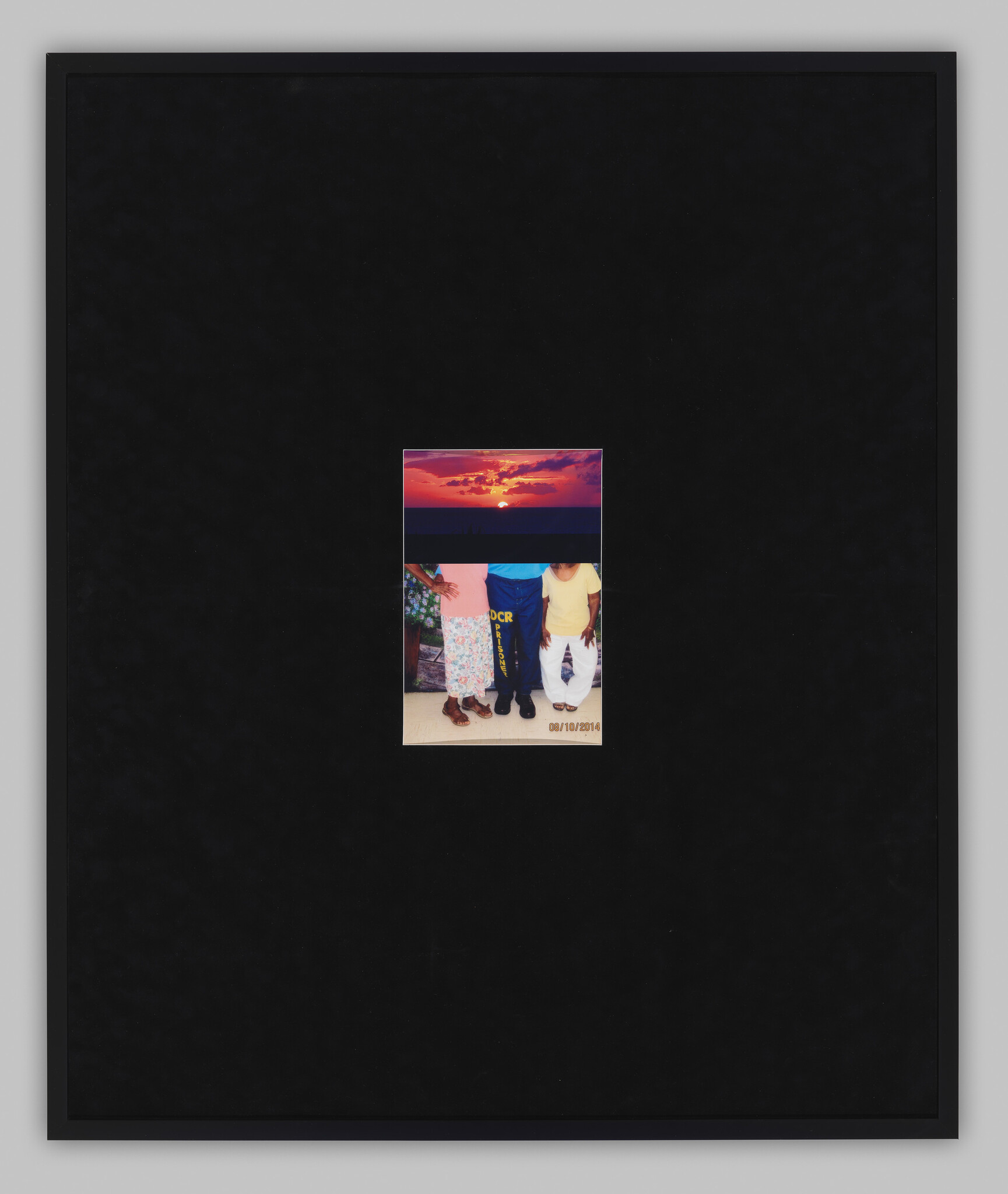 Small photograph centered on a large black background showing three people standing and a sunset above.