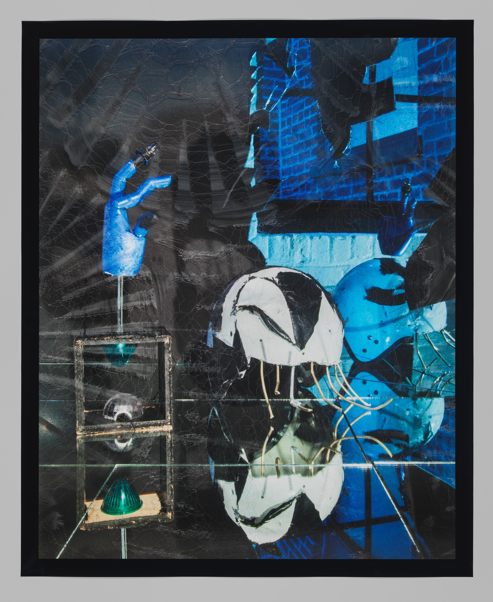 A vibrant mixed media artwork featuring abstract elements in blue and black tones with highlights of white and green. The composition includes a prominent blue hand, architectural forms, and geometric shapes, all layered with textured, crackled effects. The piece is framed in black.