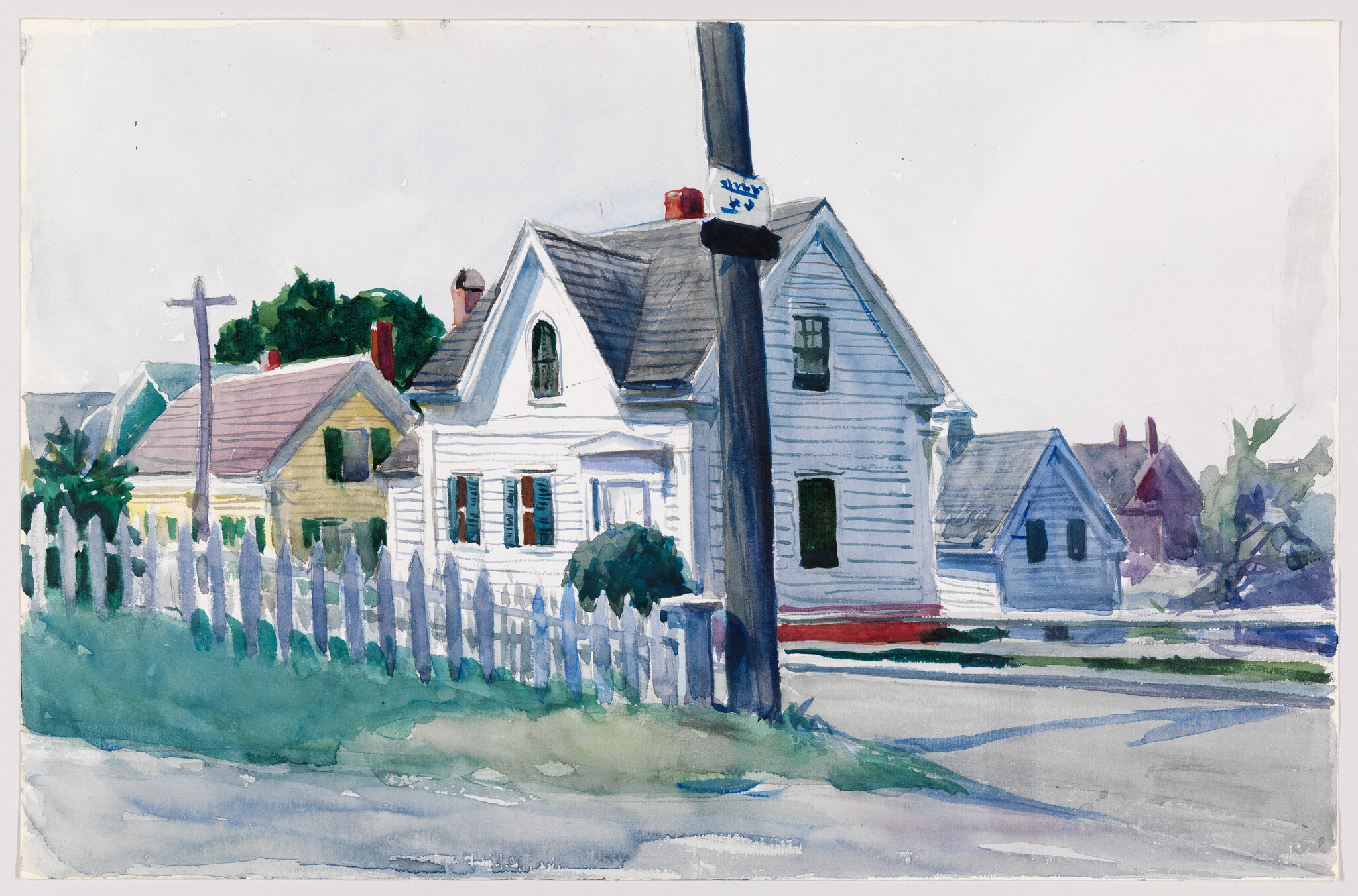 A watercolor painting depicting a quaint residential street scene with a white house featuring a gabled roof and a front porch, surrounded by a white picket fence. A utility pole with a street sign is prominently positioned in the foreground, while other houses in varying colors can be seen in the background under a light blue sky. The scene conveys a serene, small-town atmosphere.