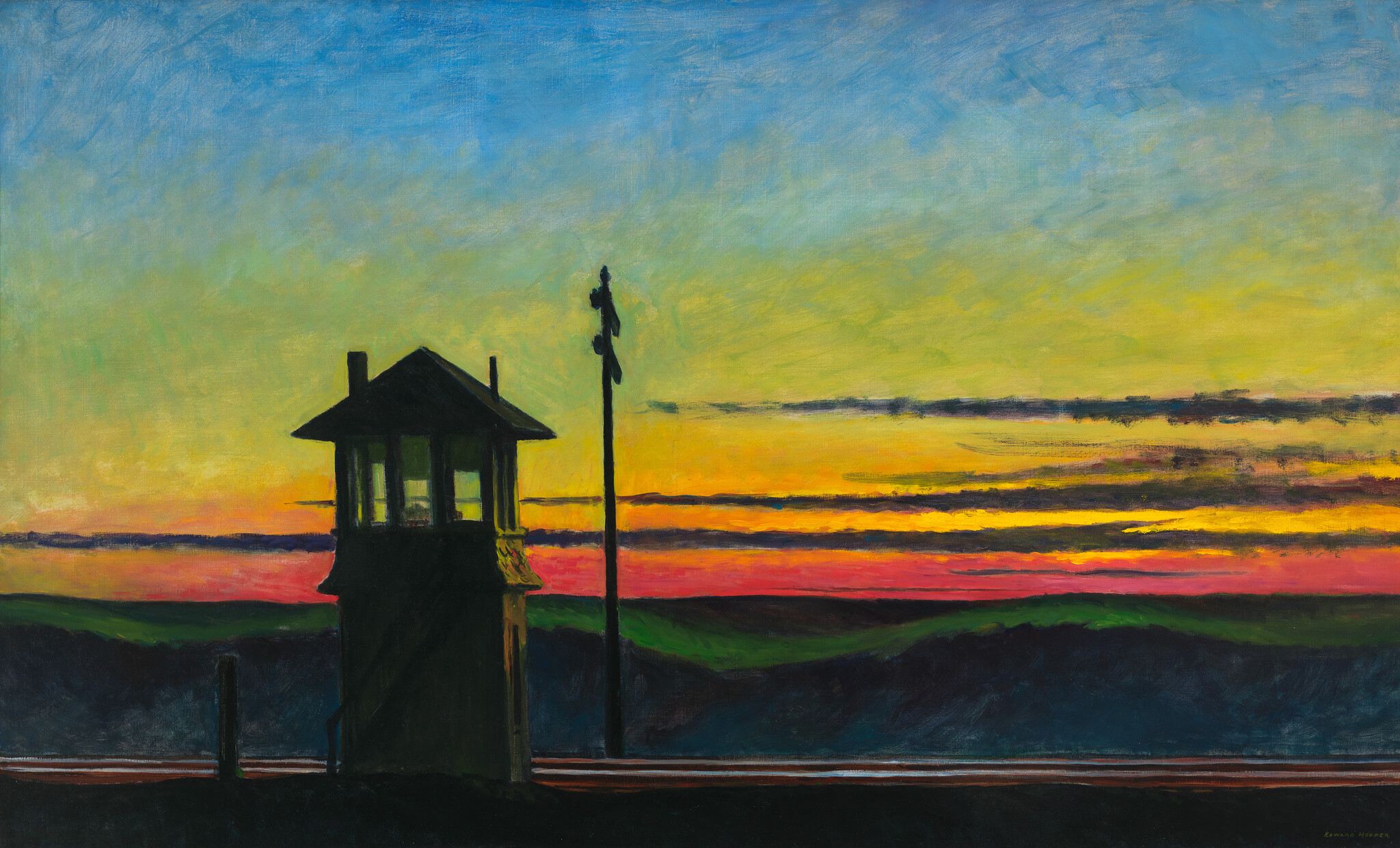 A dark railroad signal tower stands silhouetted against a vibrant yellow, pink, and blue sunset.