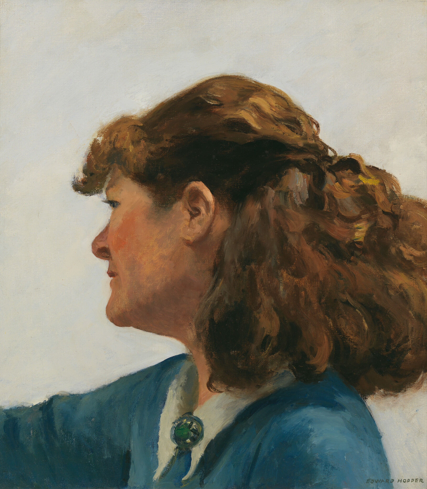 A white woman wearing a blue top with a white collar is gazing her attention away. She has flushed cheeks and brown fluffy curly hair