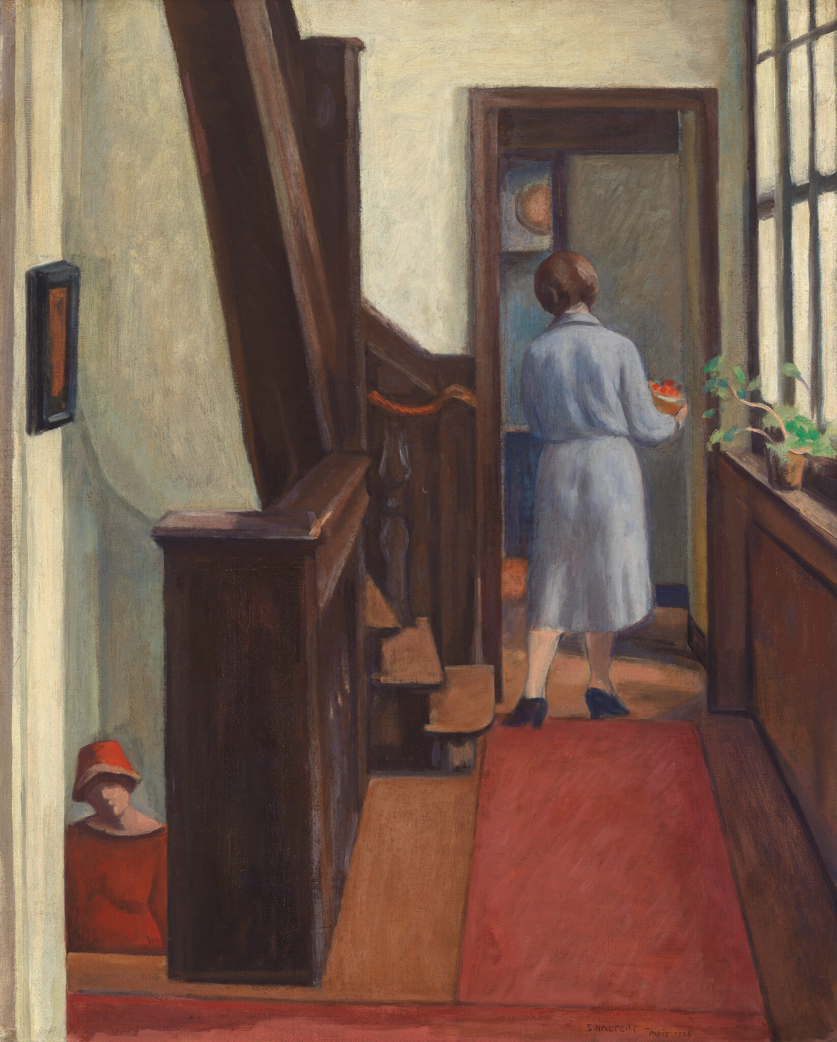 A woman in a light dress carries a bowl of red fruit down a narrow hallway.