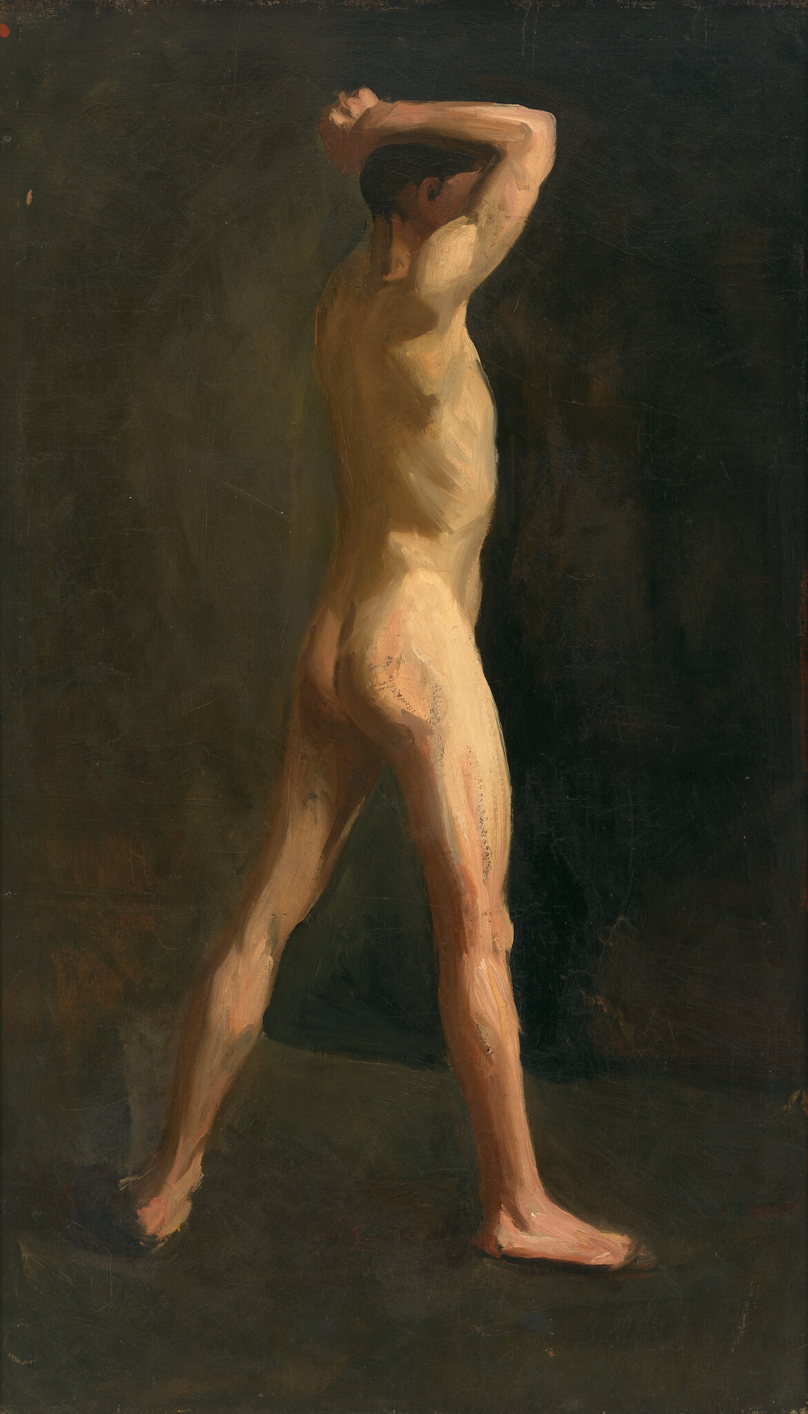 A nude male model stands with his arms raised behind his head and legs apart.