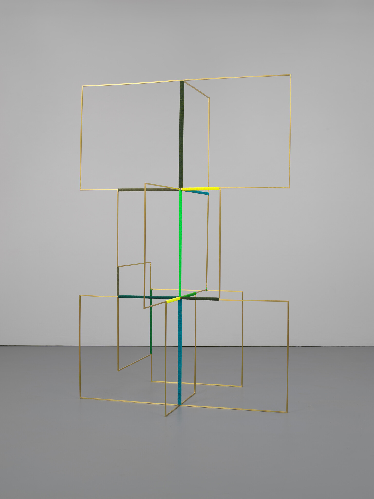 A tall geometric metal sculpture of gold rectangular frames connected by green, blue, and yellow vertical supports.