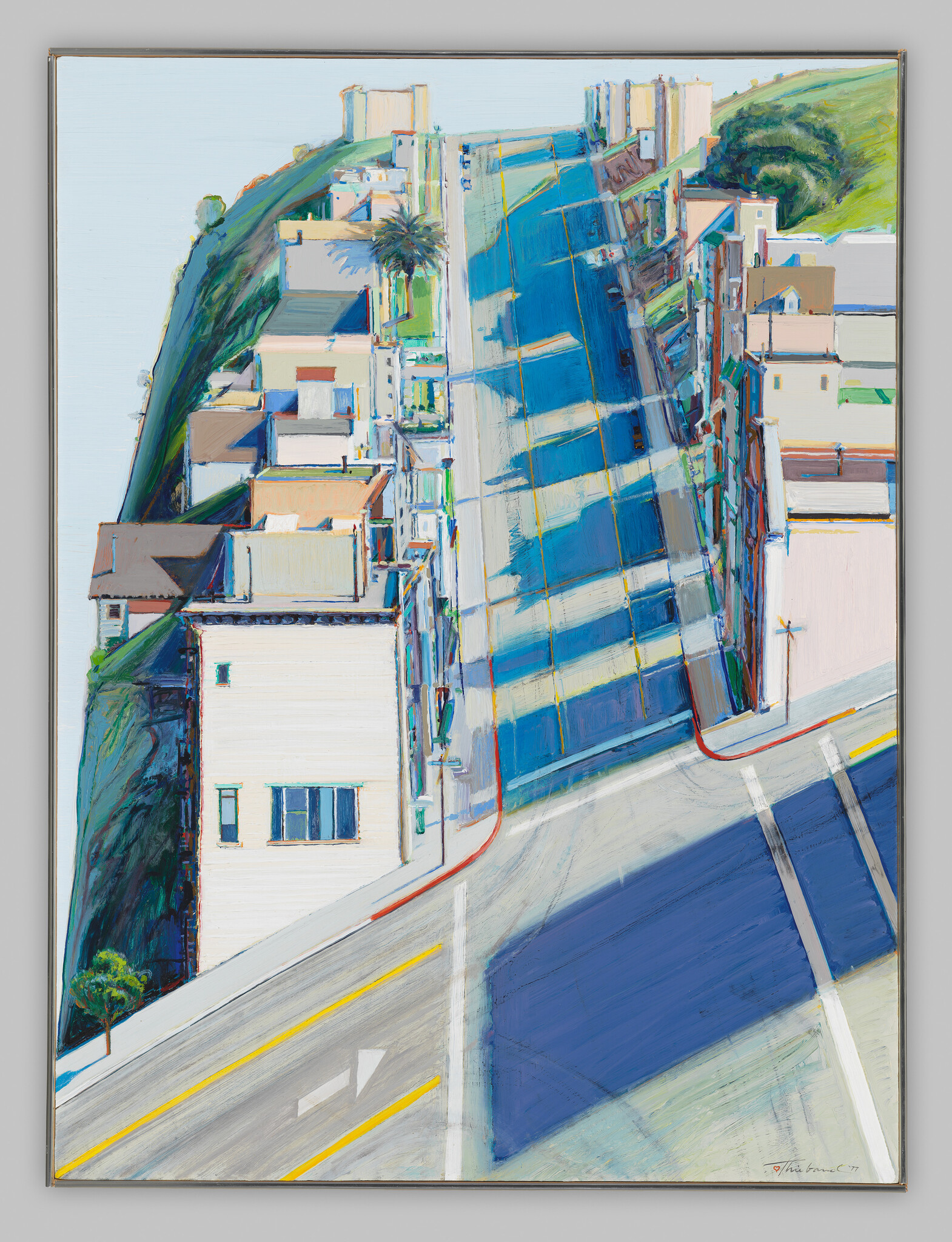 A steep city street with houses on both sides, strong blue shadows, and yellow road lines.