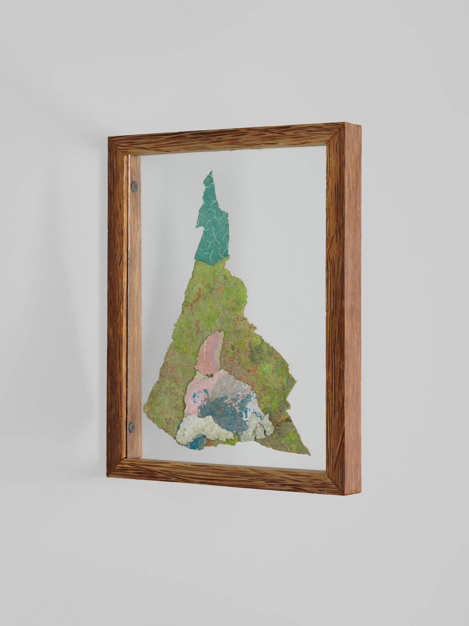 Wooden-framed artwork shows a textured, multicolored map-like shape mounted on a gray wall.