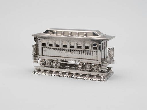 A detailed silver model of a vintage passenger railcar displayed on a short section of track.