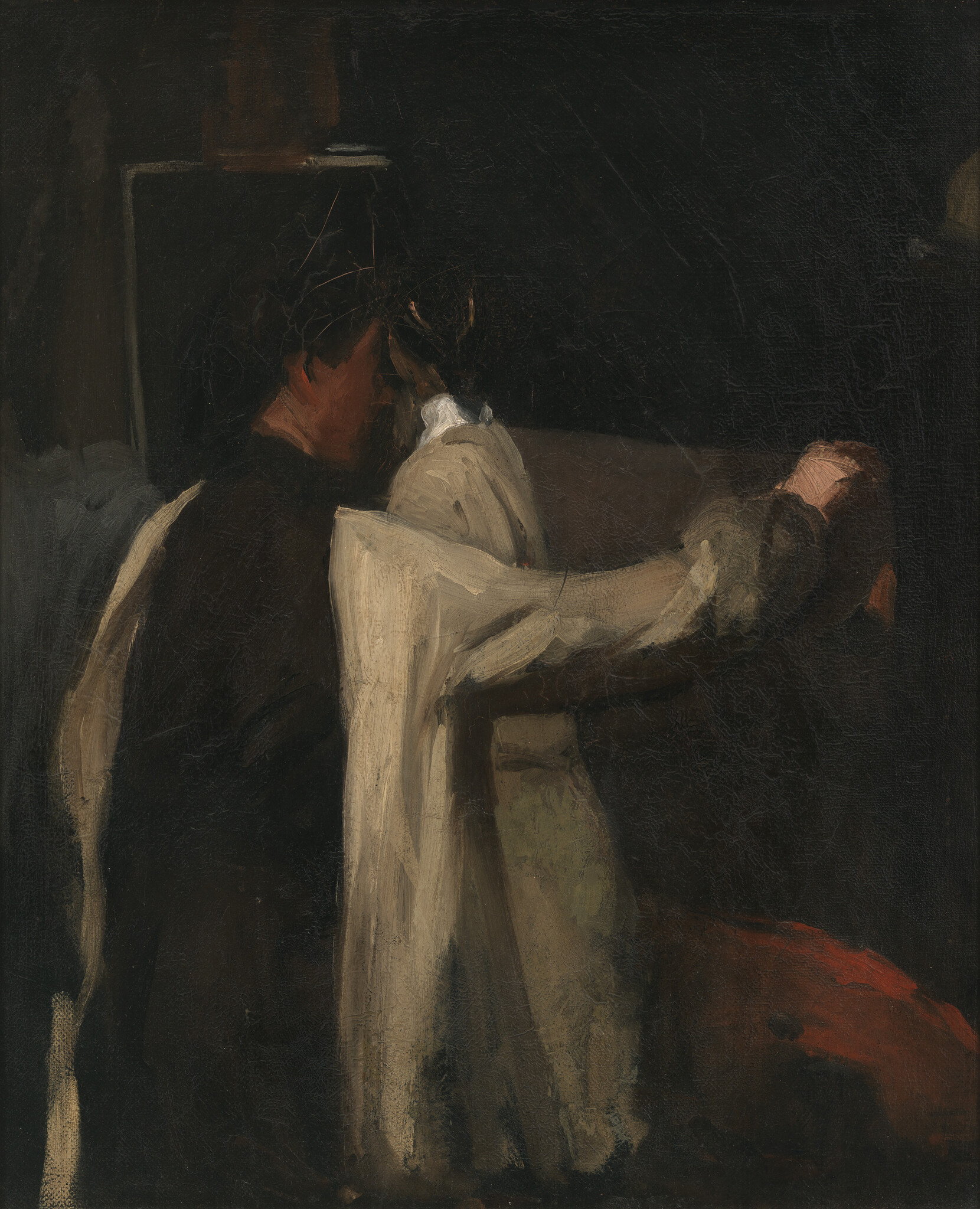 A couple embraced in dim light, one person wearing a white garment and holding the other's shoulder.
