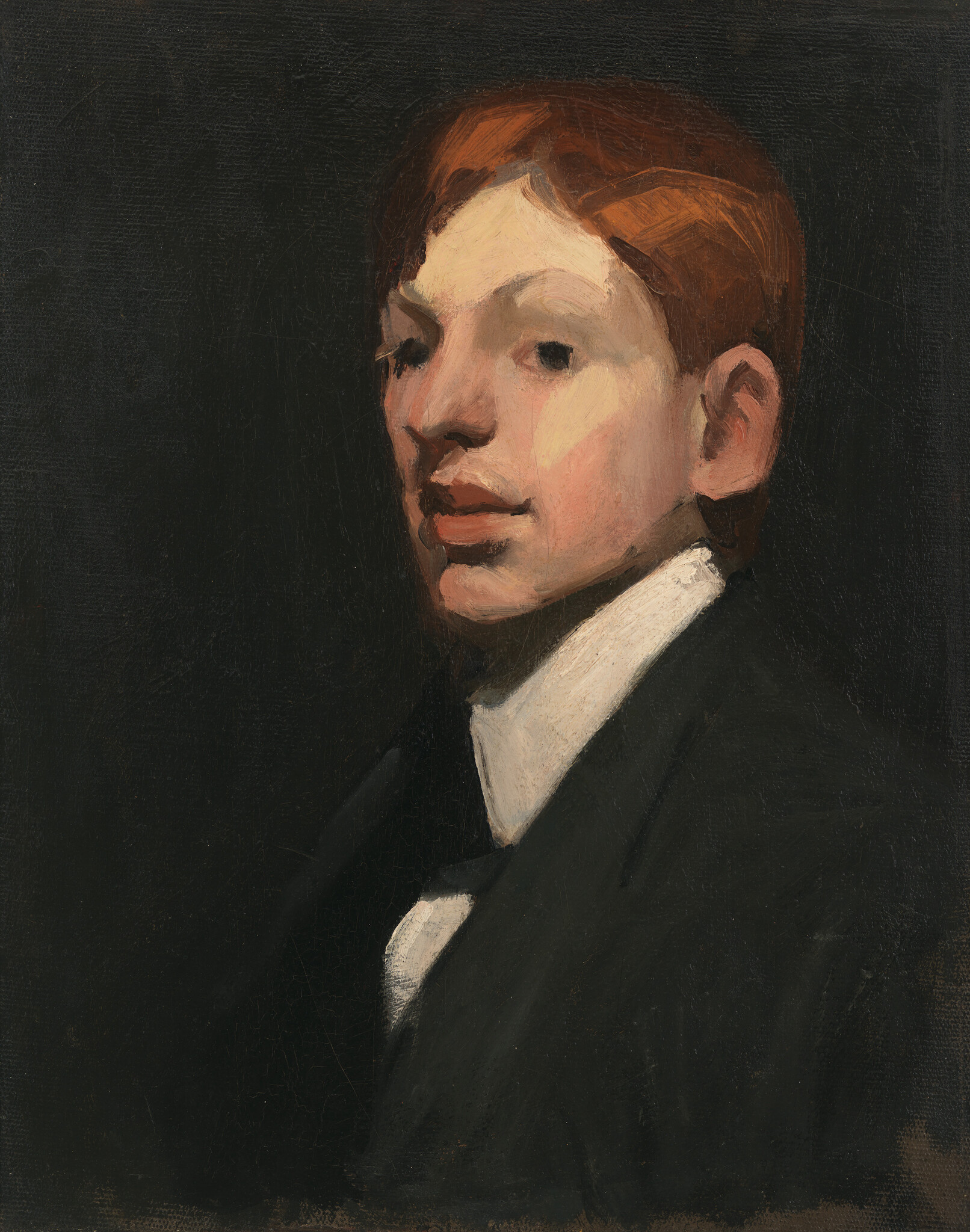 Young red-haired man wearing a dark suit and white collar looks slightly to the side.