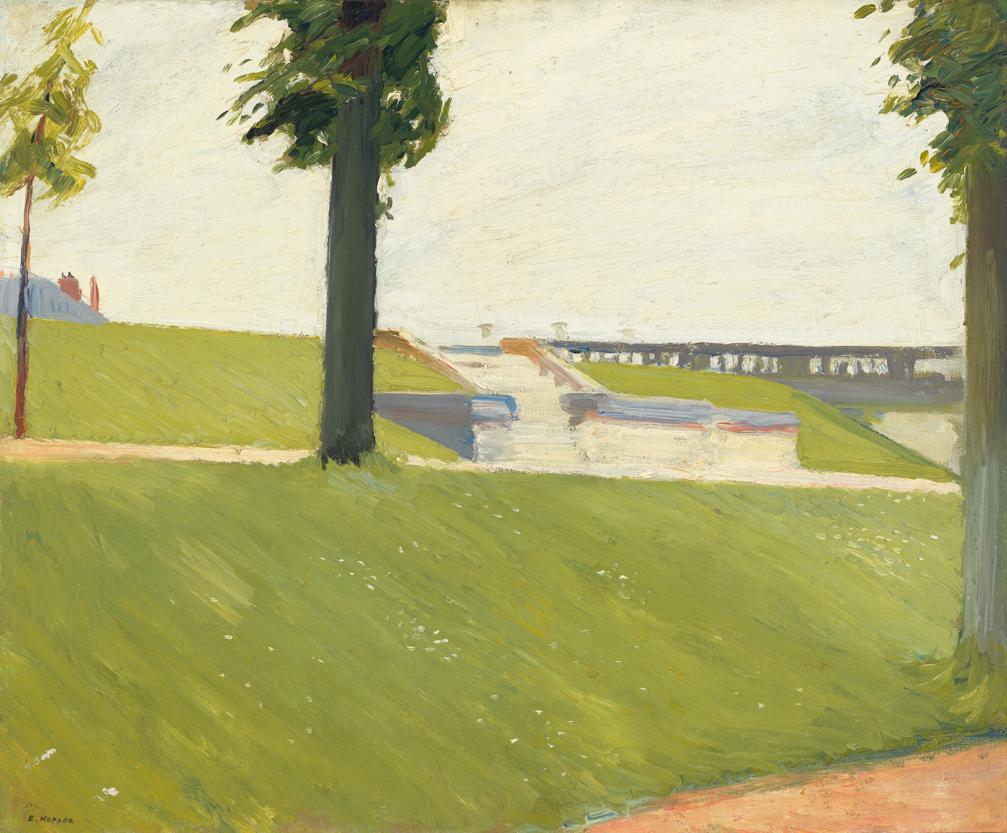 Two large trees frame a sunlit grassy park with a canal and low bridge in the distance.