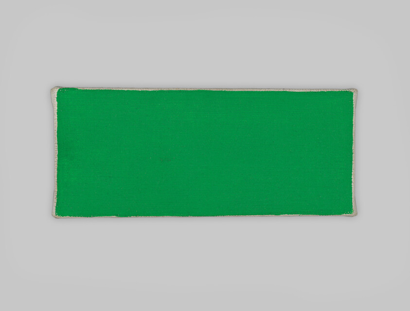 A rectangular green fabric patch with stitched beige edges centered on a light gray background.