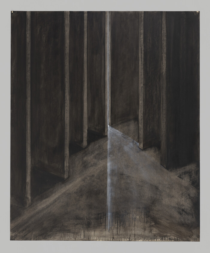 Tall dark pillars create a narrow opening with a thin beam of light on a dusty floor.