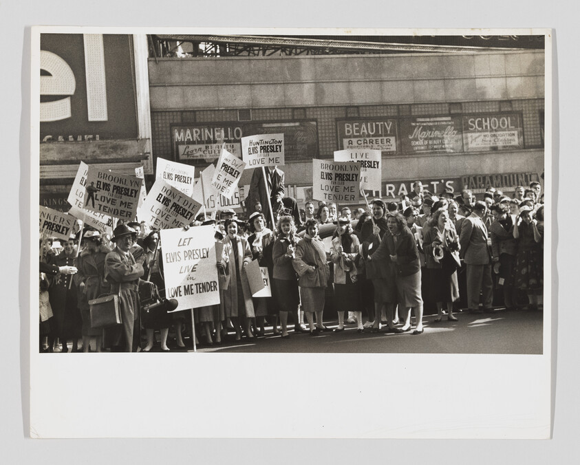 A large crowd of fans holding signs urging support for Elvis Presley and "Love Me Tender."