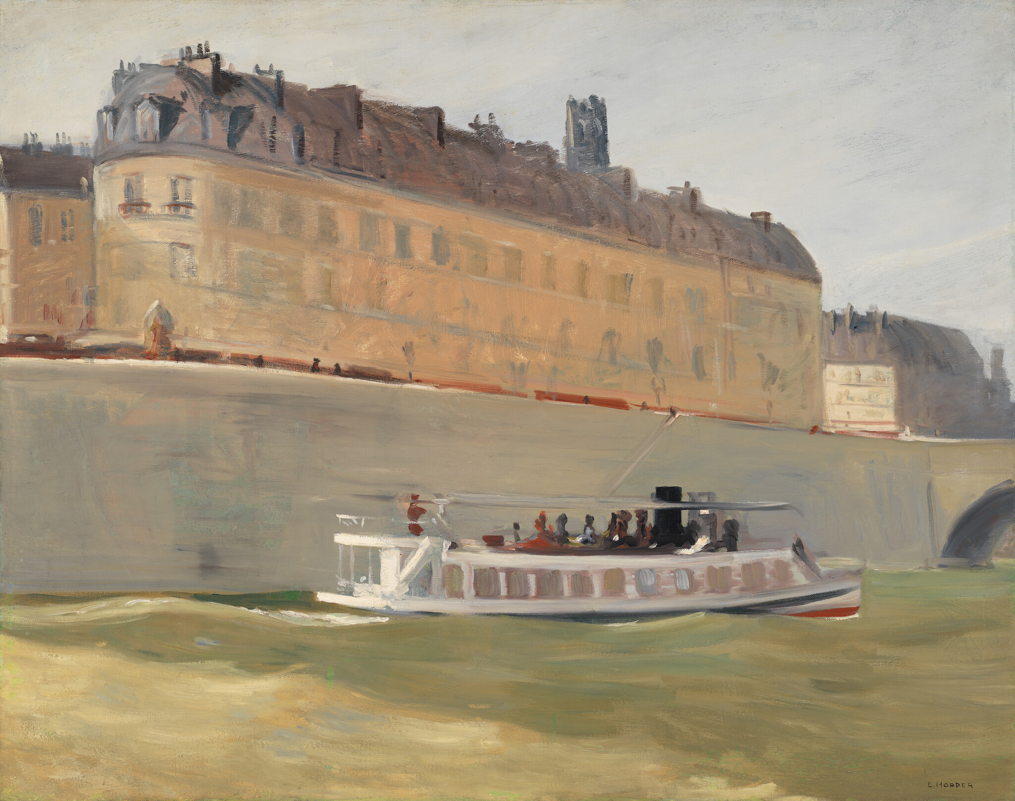 A small passenger boat moves along a river past a large sunlit riverside building.