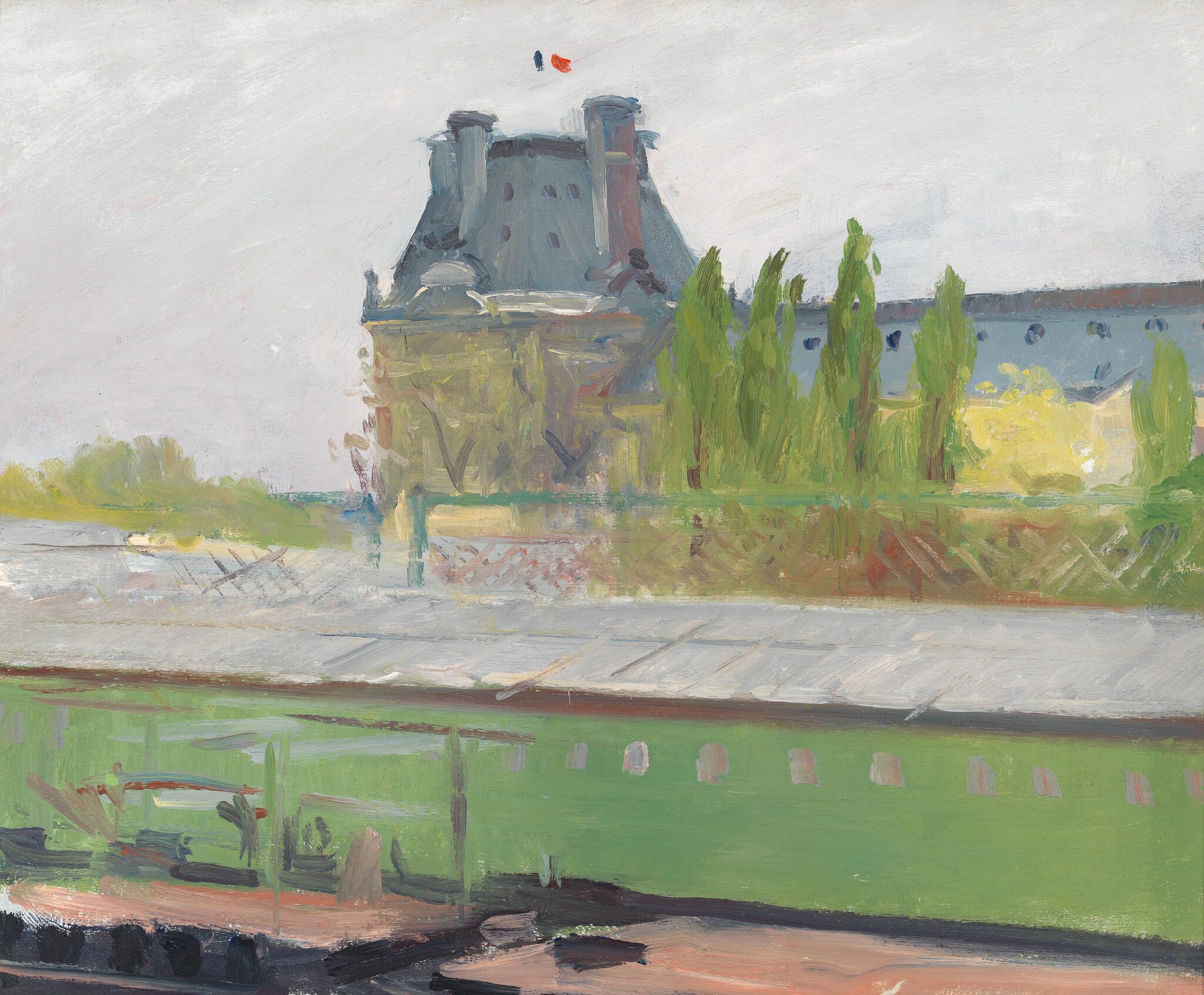 A riverside building and tall trees stand behind a stone quay and green embankment.