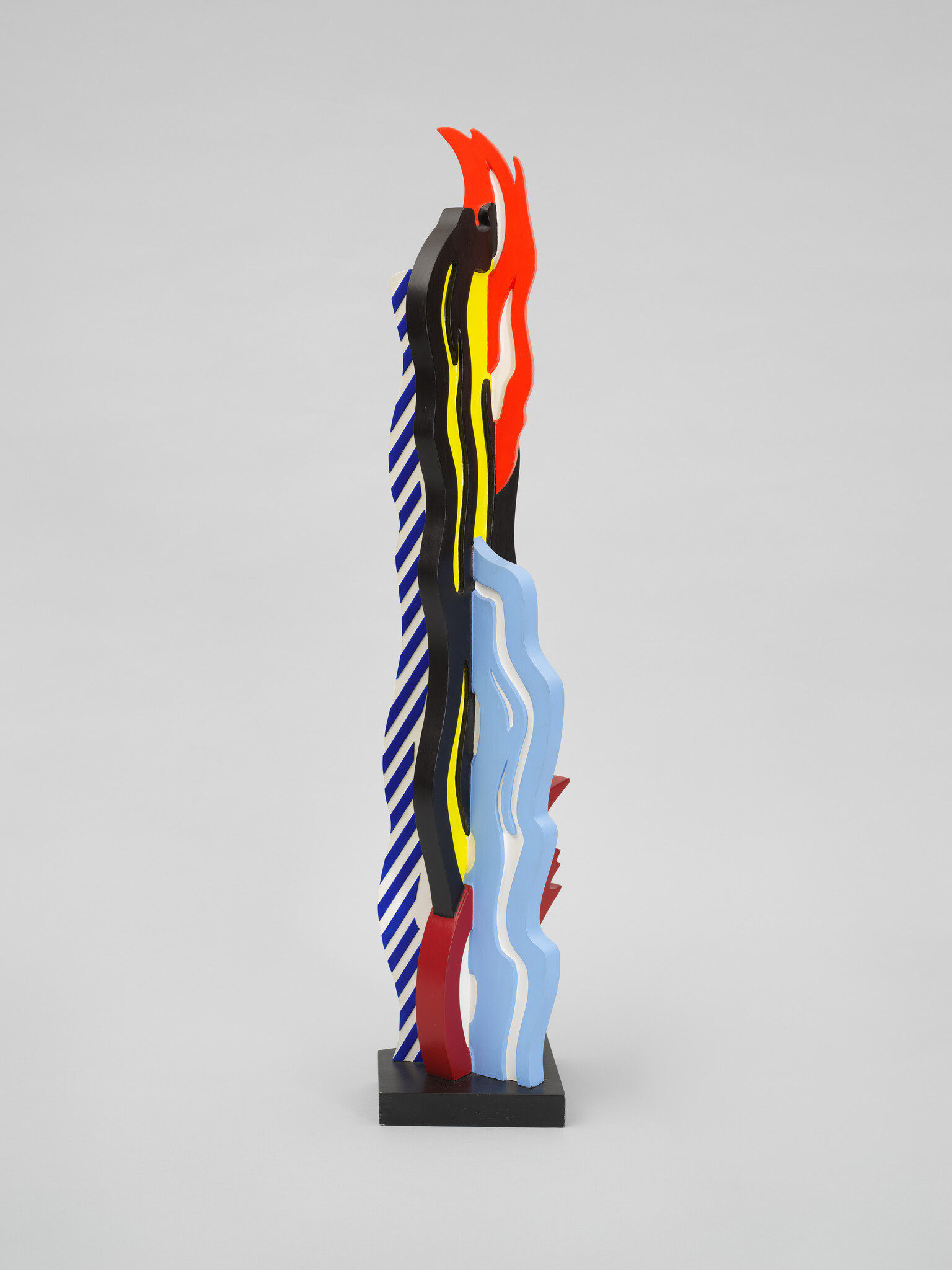 Tall vertical sculpture with layered wavy panels in red, blue, yellow, black, and white.