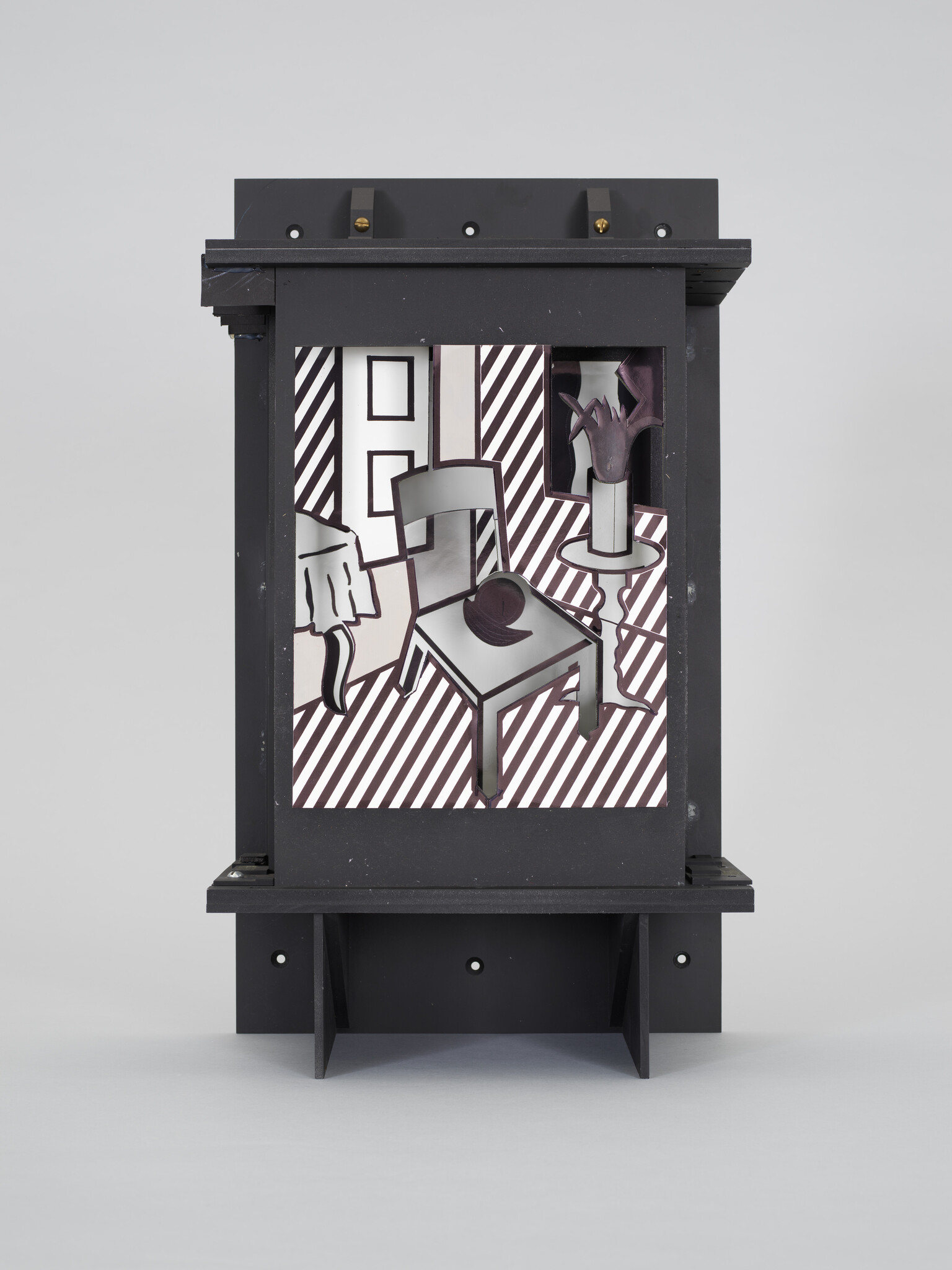 Black wooden display box containing a stylized interior scene with chair, table, vase, and diagonal stripes.