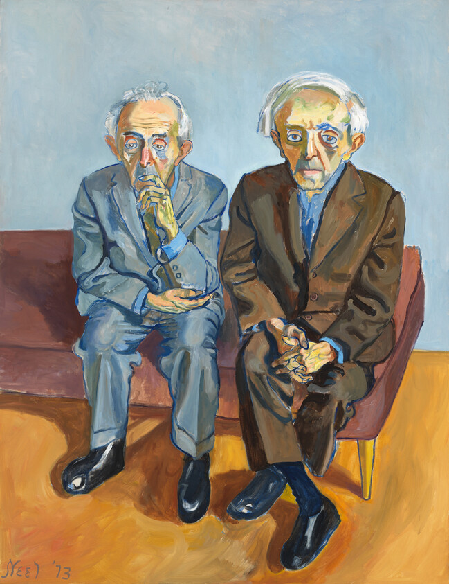 Two elderly men in suits sit side by side on a couch, looking thoughtful and clasping hands.