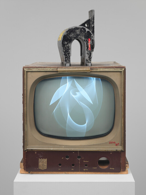 Old television with abstract blue light on screen and a large metal clamp resting on top.