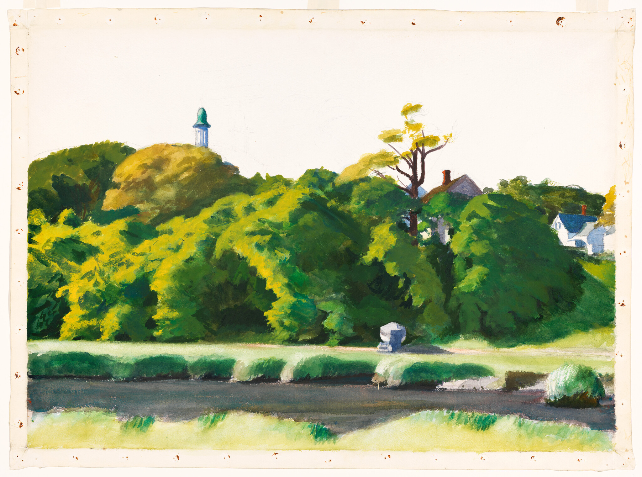 Lush green trees and bushes along a riverbank with houses and a small tower peeking above.