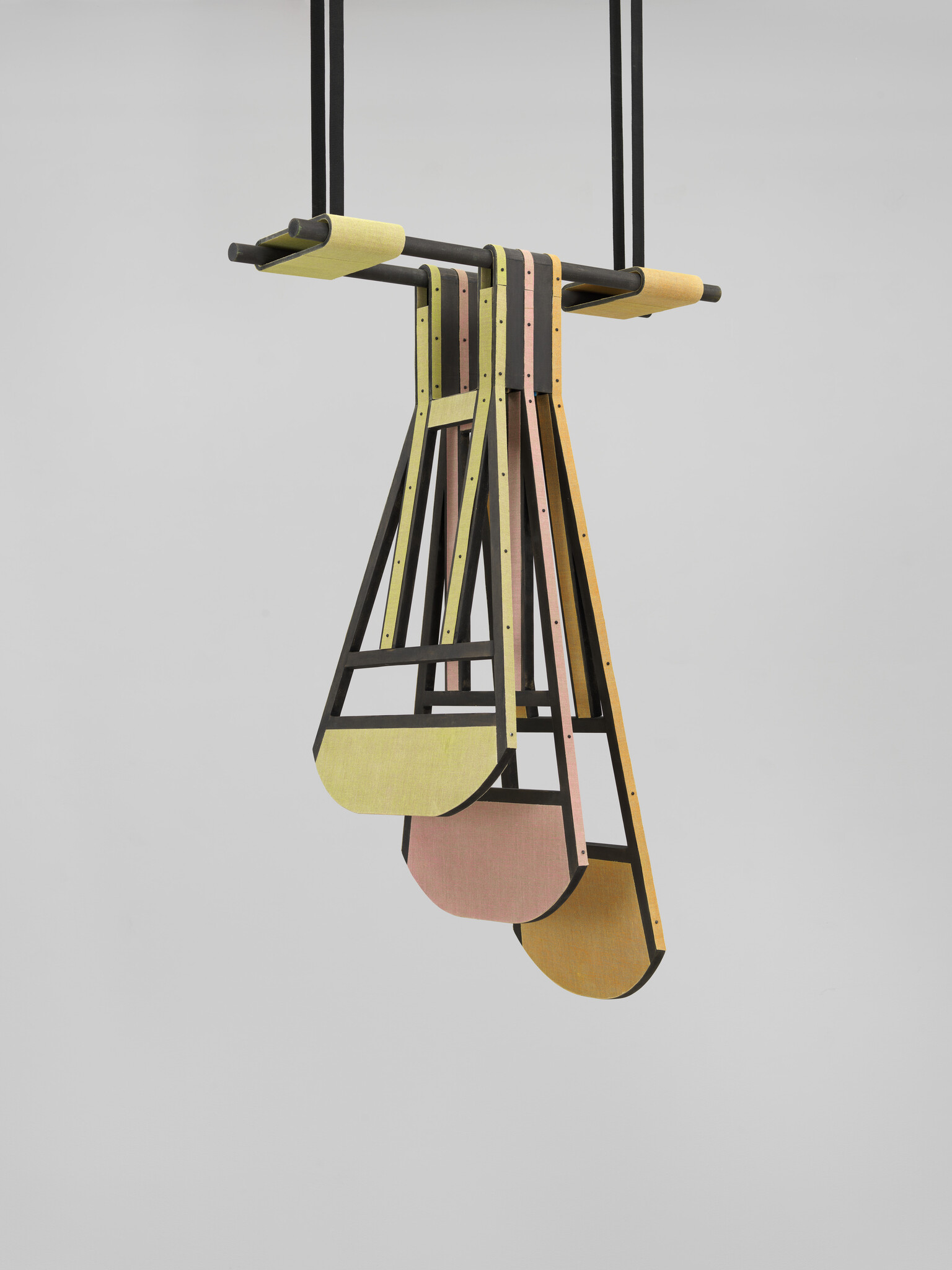 Three suspended wooden swing seats with pastel-colored panels hang from a black horizontal bar.