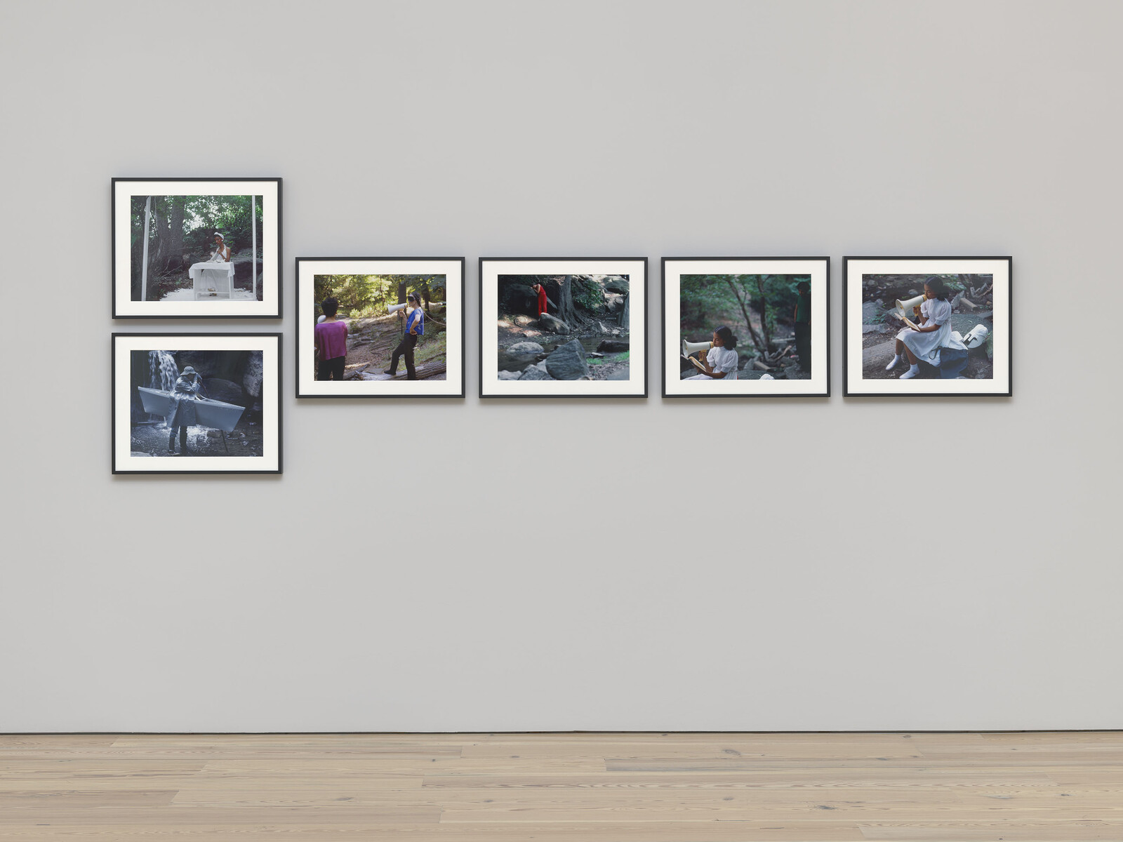 Six framed photographs of people exploring and reading outdoors hung in a simple gallery arrangement.
