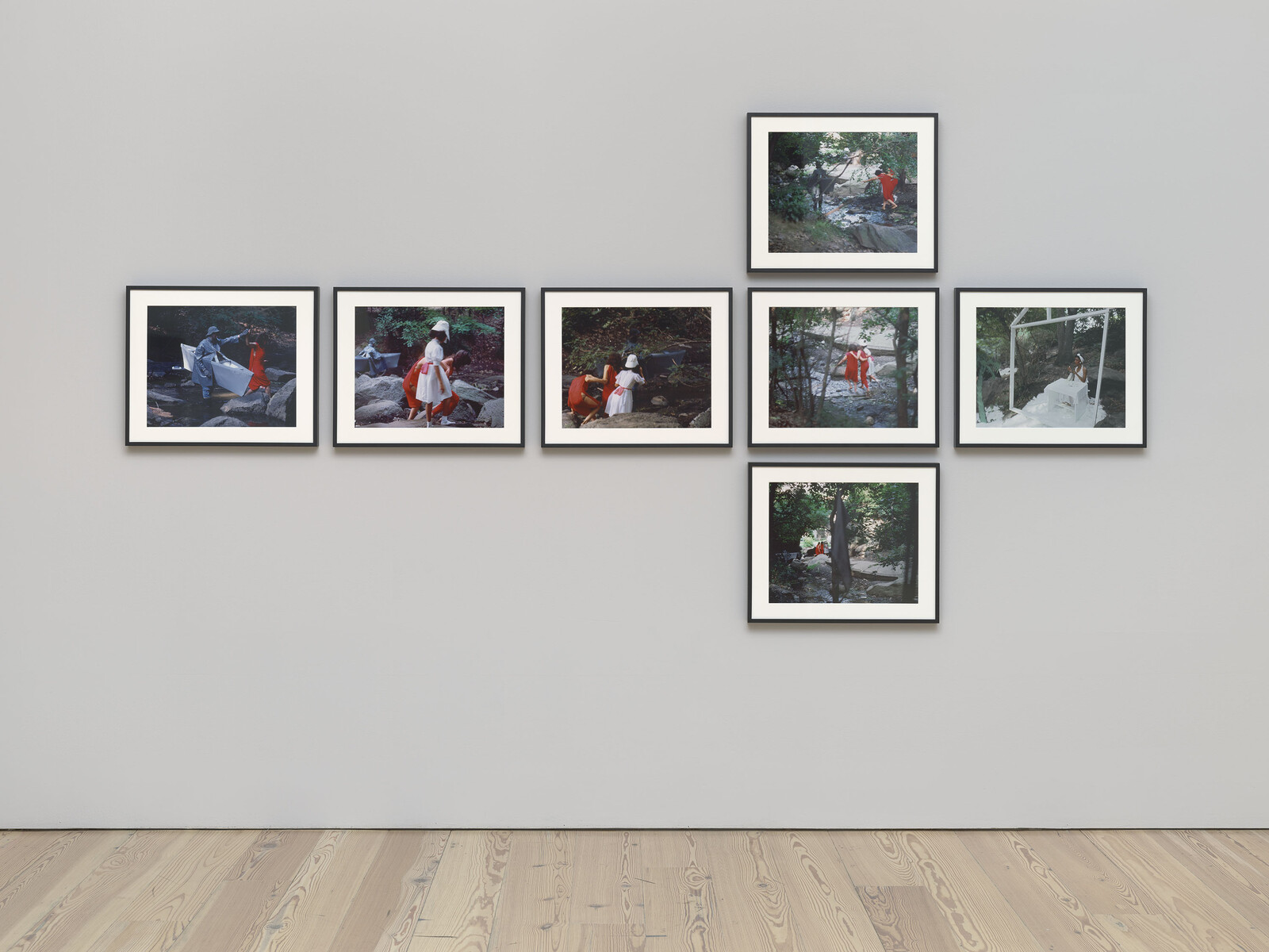 Eight framed photographs show people in red and white exploring a wooded rocky stream.