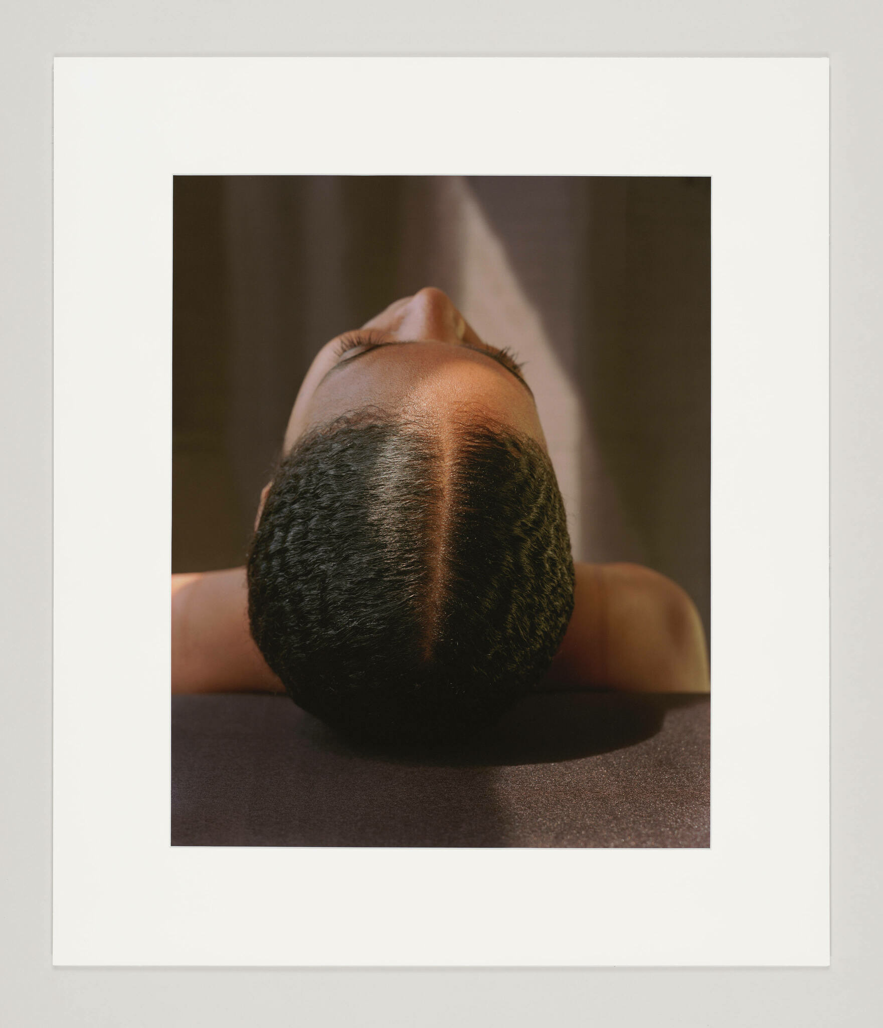 The top of a Black woman's head as she leans back, her hair slicked down and parted. 