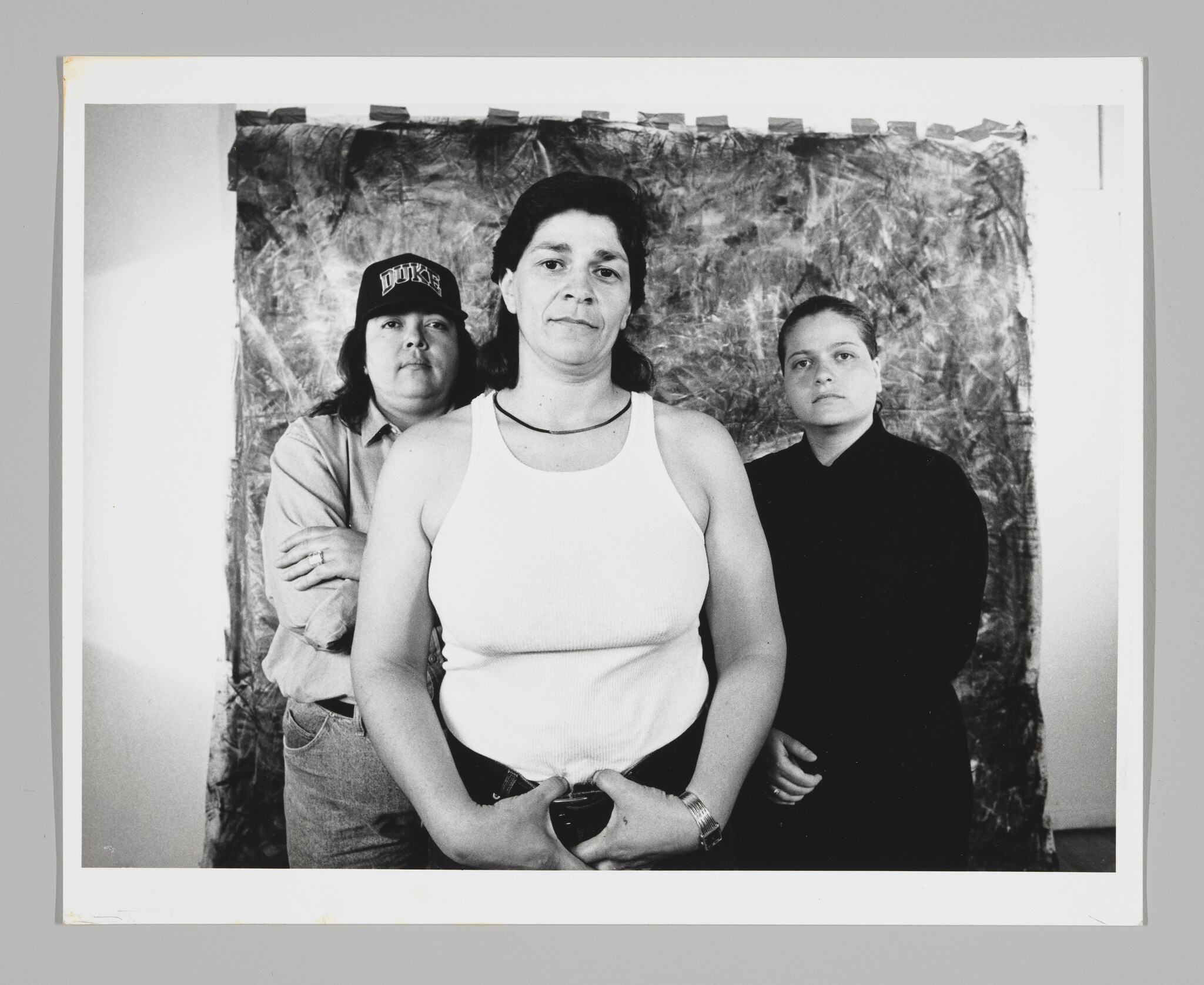 Three figures stand in front of a studio photography backdrop