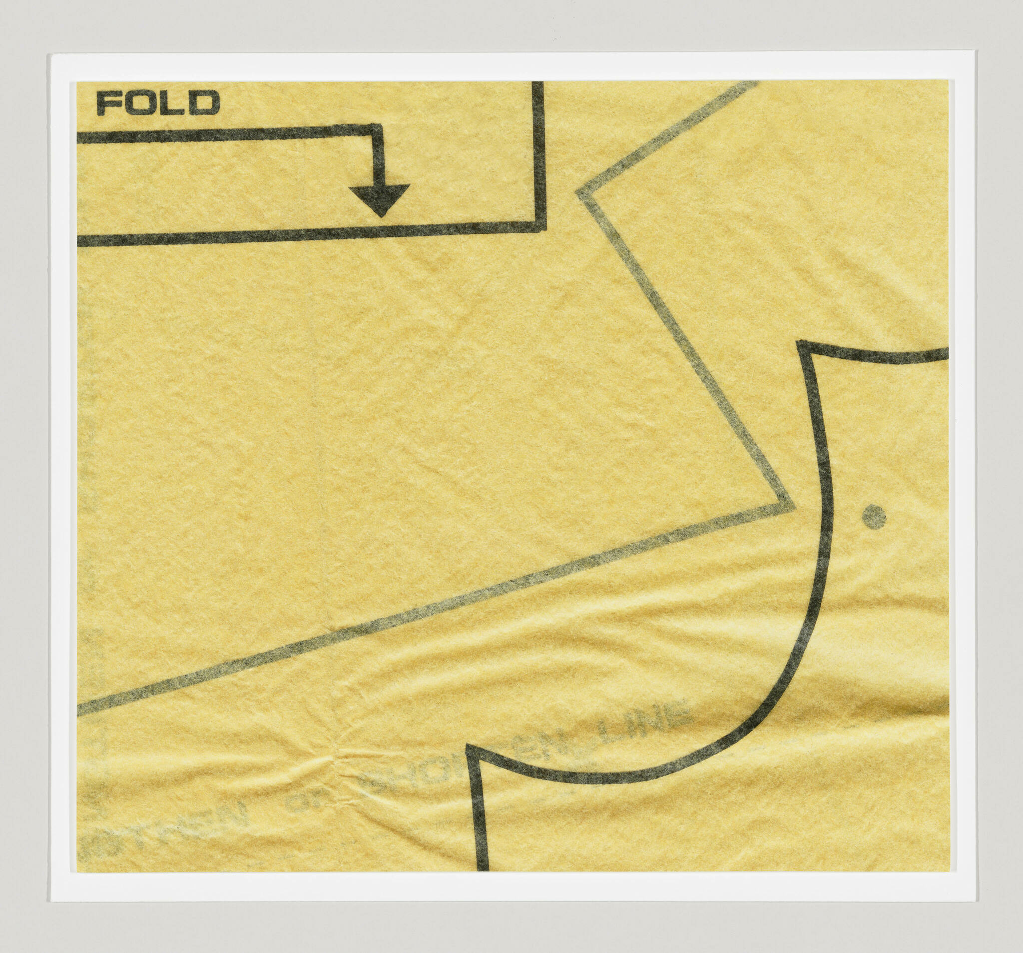 Detail of yellow tissue sewing pattern with printed curves, lines, and text reading FOLD with a directional arrow.