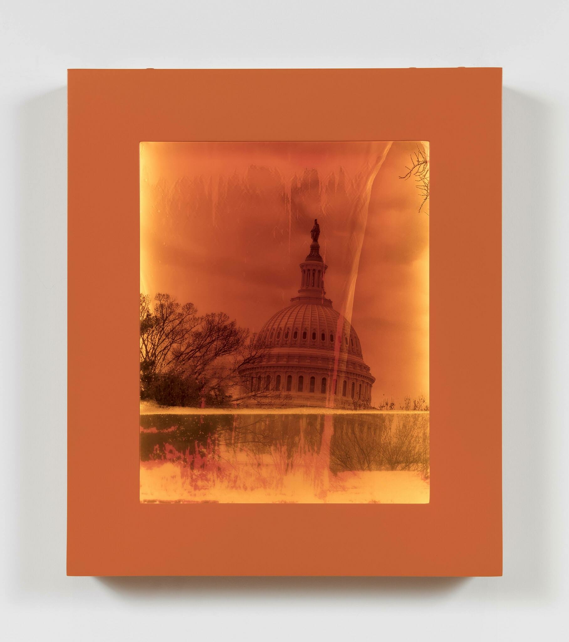 Photo of the United States Capitol building contained within an orange frame filling with water