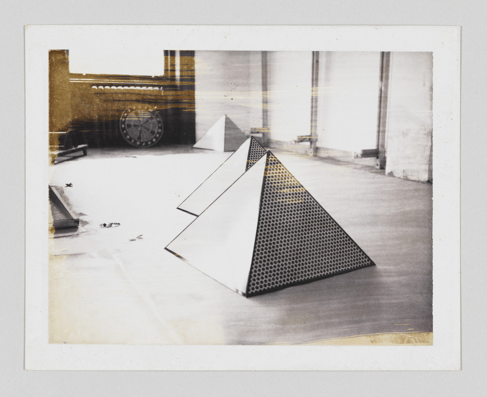 Three geometric pyramid sculptures arranged on a wooden floor, the nearest with a honeycomb pattern.