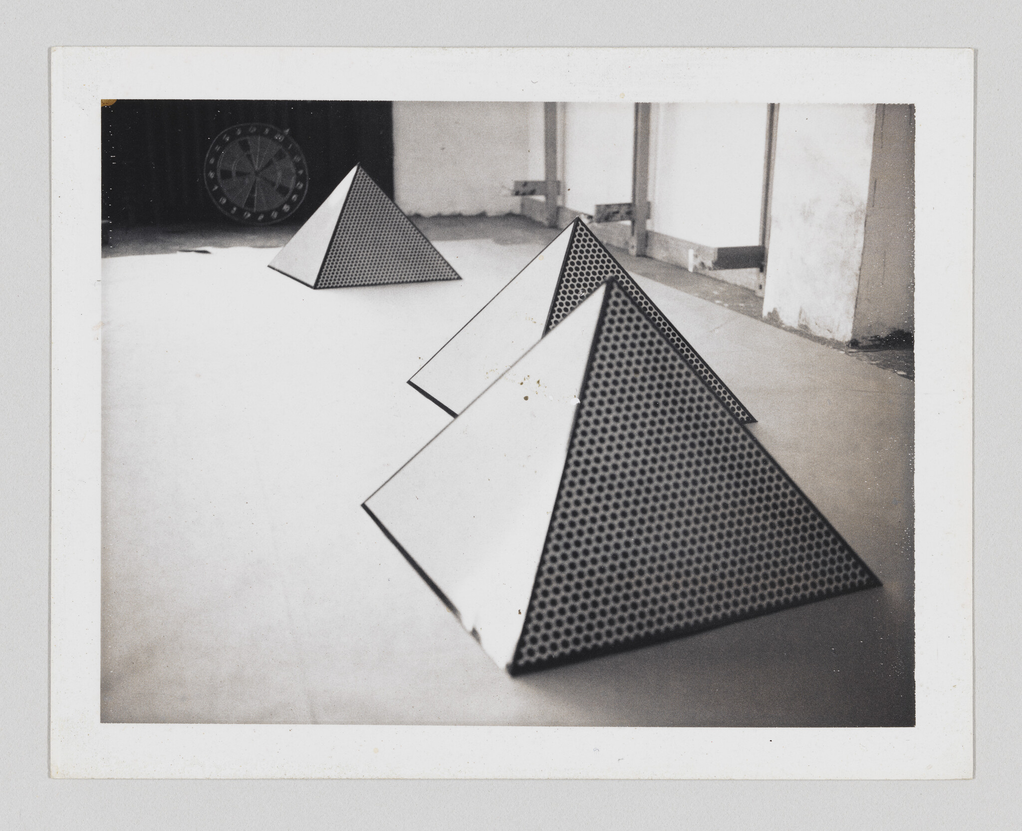 Three triangular pyramids with perforated faces are arranged in a row on a floor.