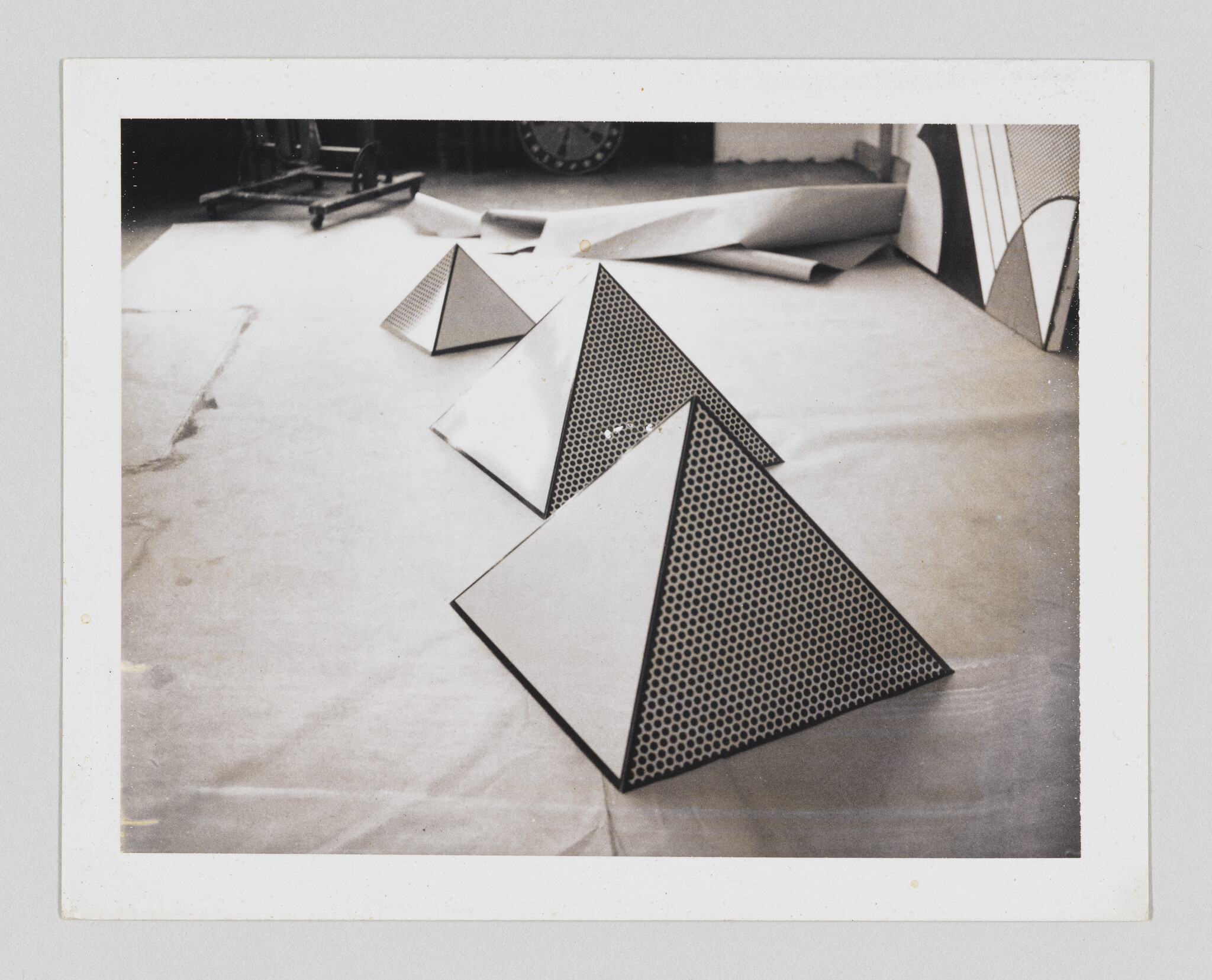 Three triangular pyramids with dotted faces are arranged in a line on a studio floor.