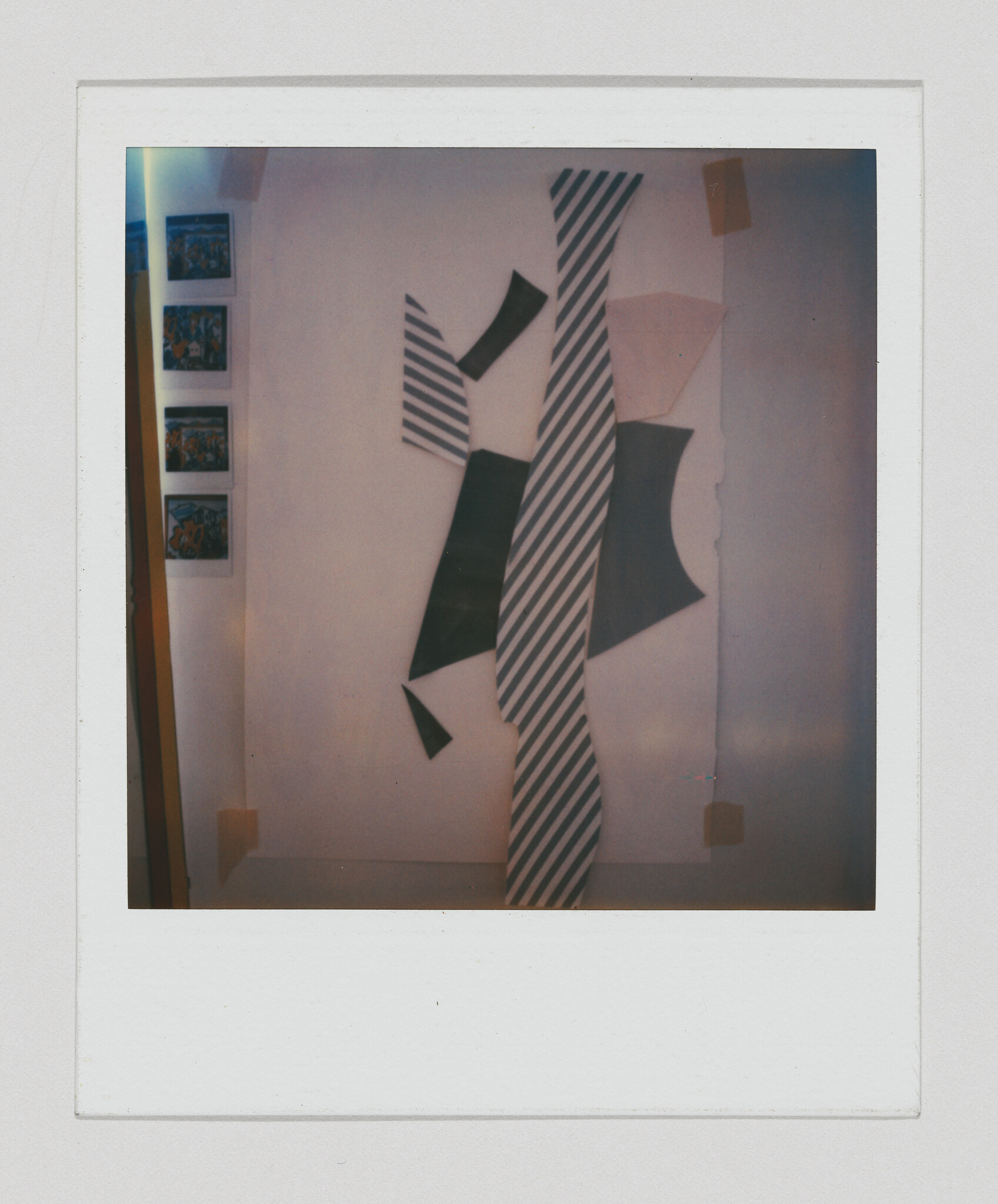Large abstract wall collage of striped and solid geometric shapes taped to a gallery wall.