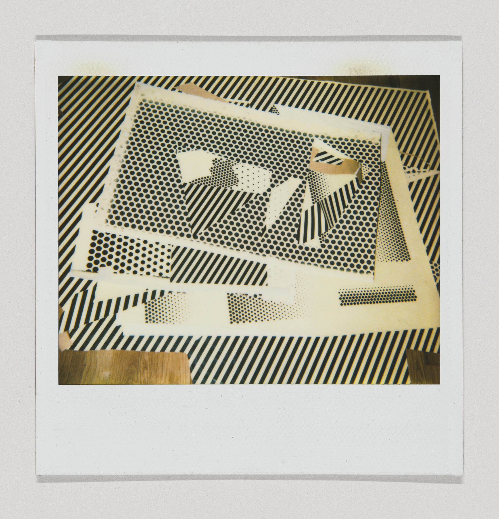 A layered collage of perforated sheets and diagonal striped papers arranged on a table.