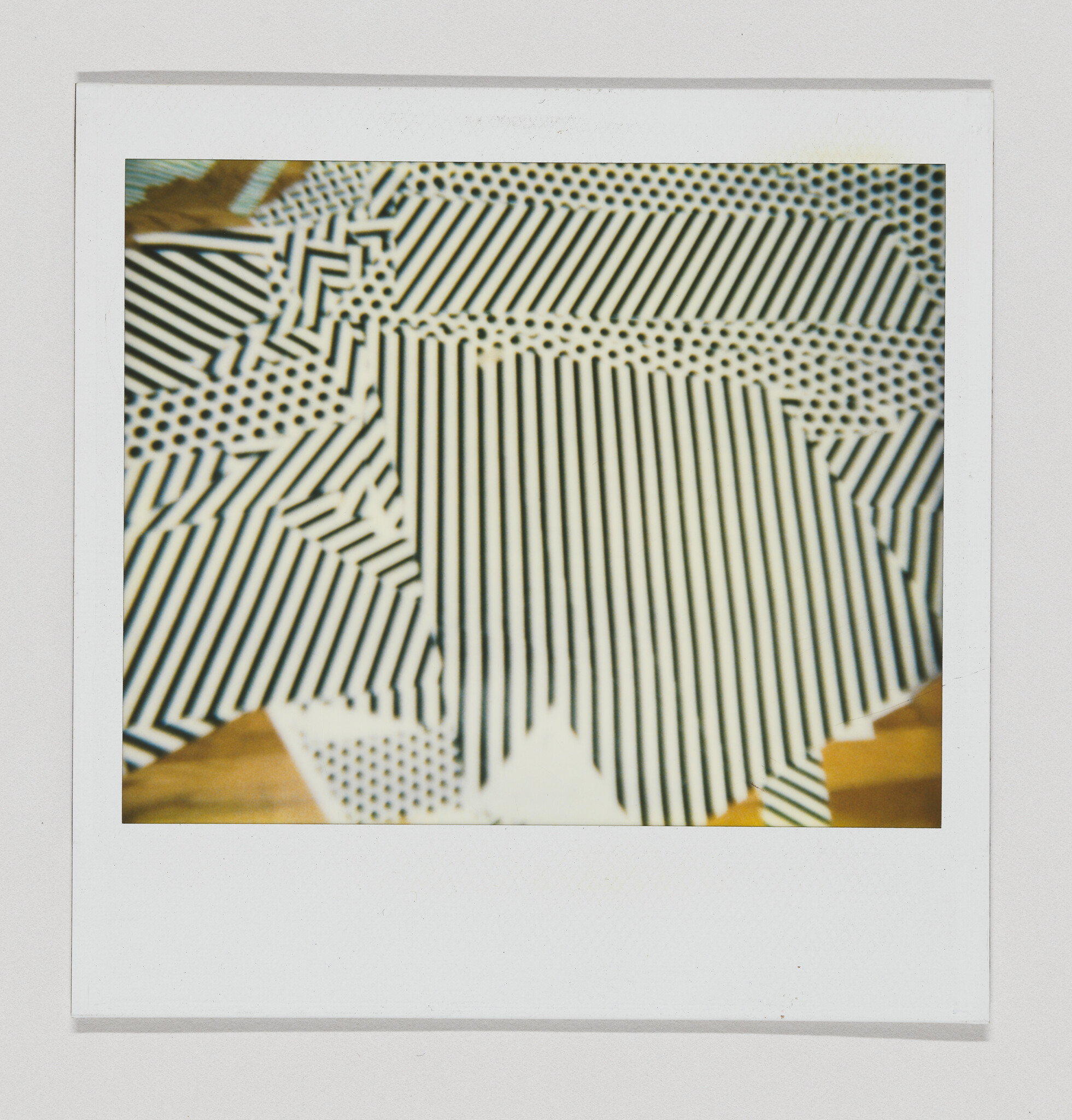 Several overlapping black-and-white striped and dotted paper sheets arranged inside a white Polaroid frame.
