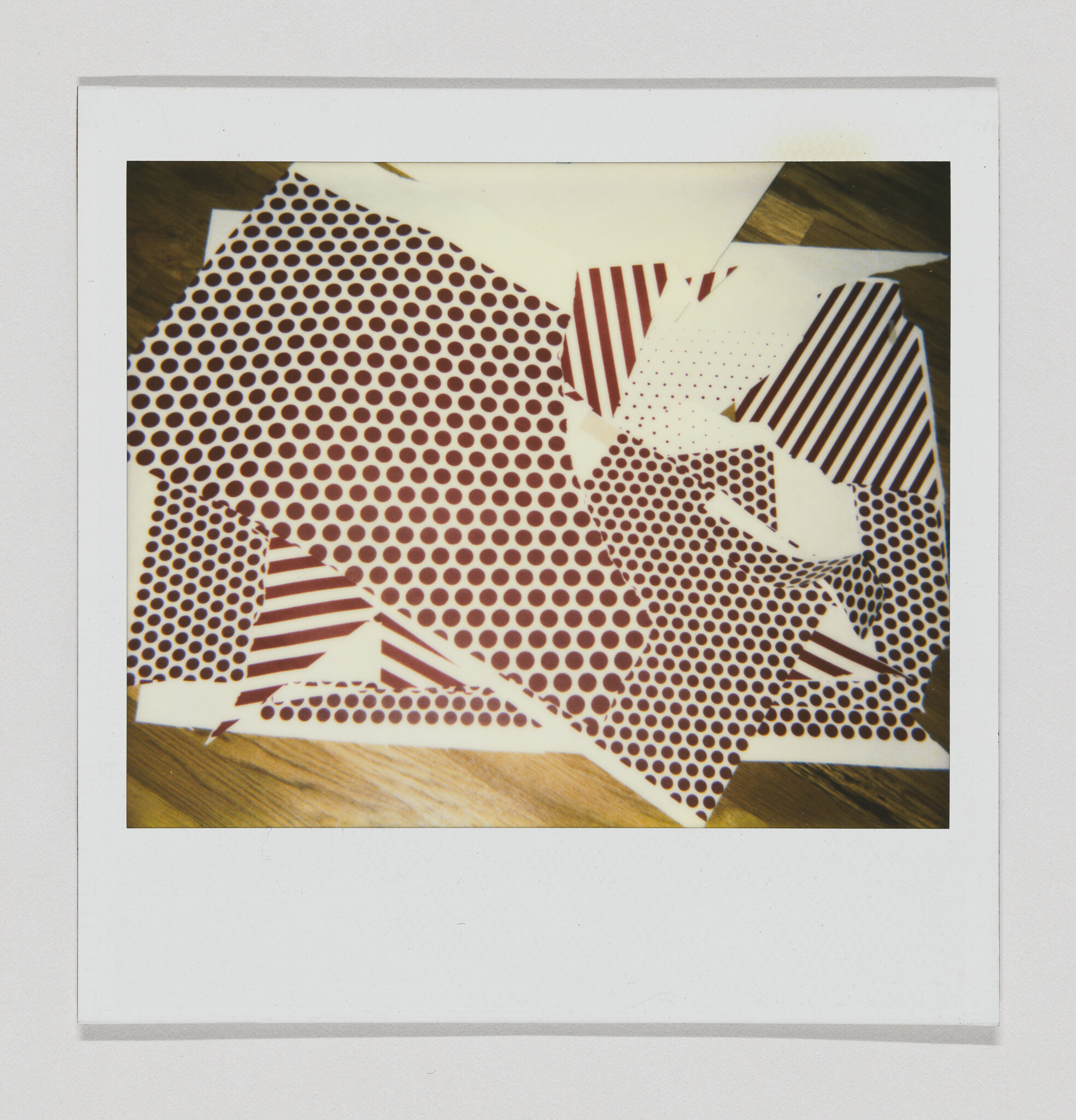 Several torn sheets of red polka-dot and striped paper scattered on a wooden floor.