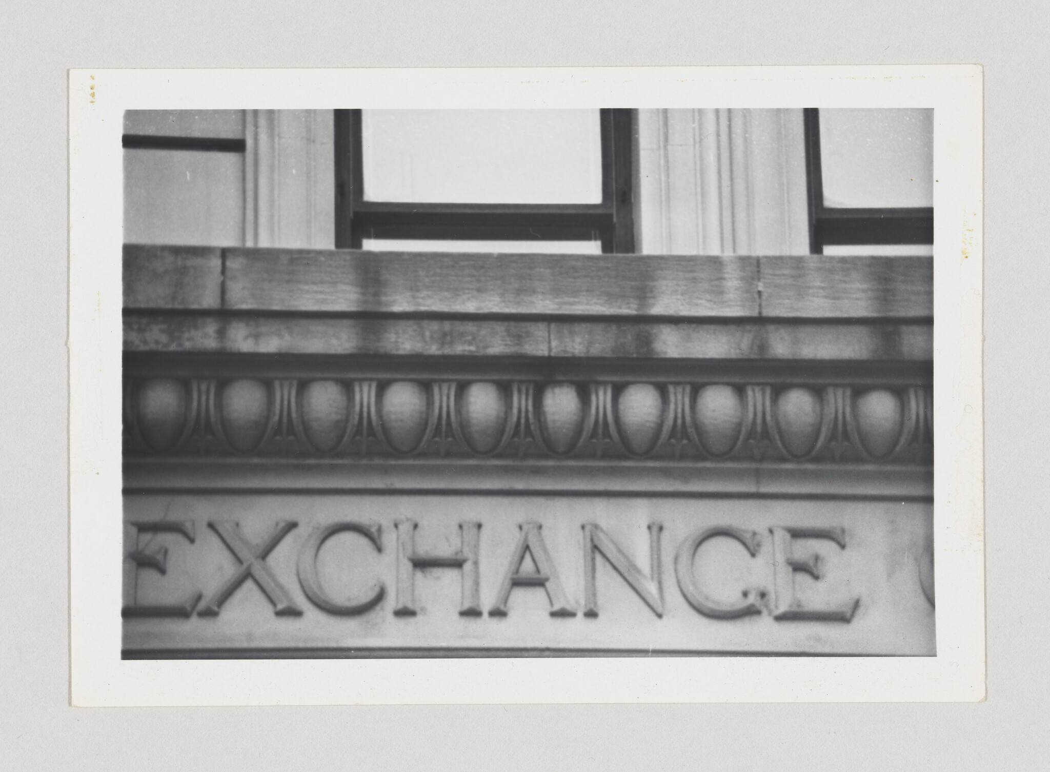 Stone building facade with decorative molding and the carved word 'EXCHANGE' across its front.