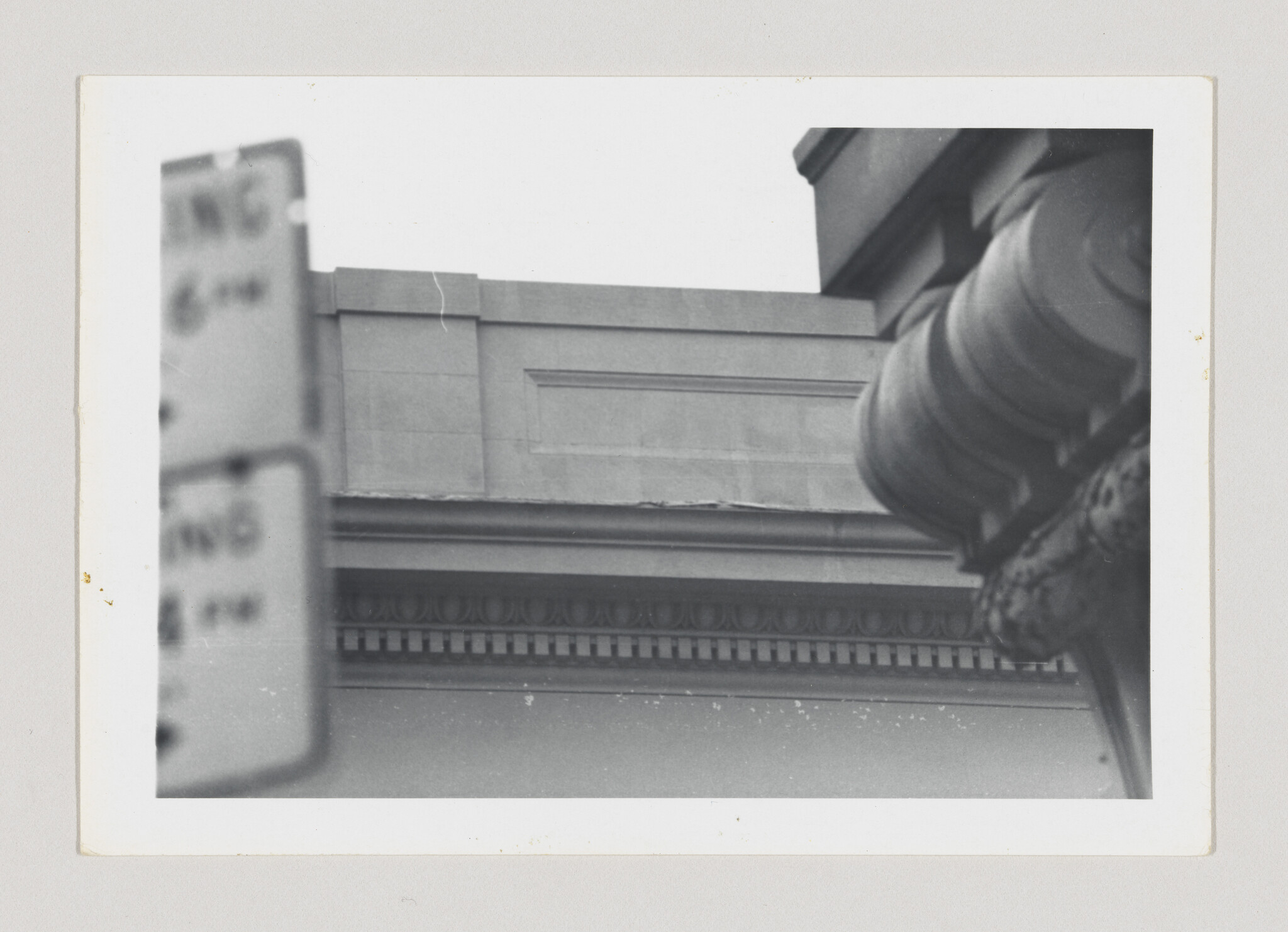 Stone building cornice with detailed molding and a rounded column ornament visible at right.