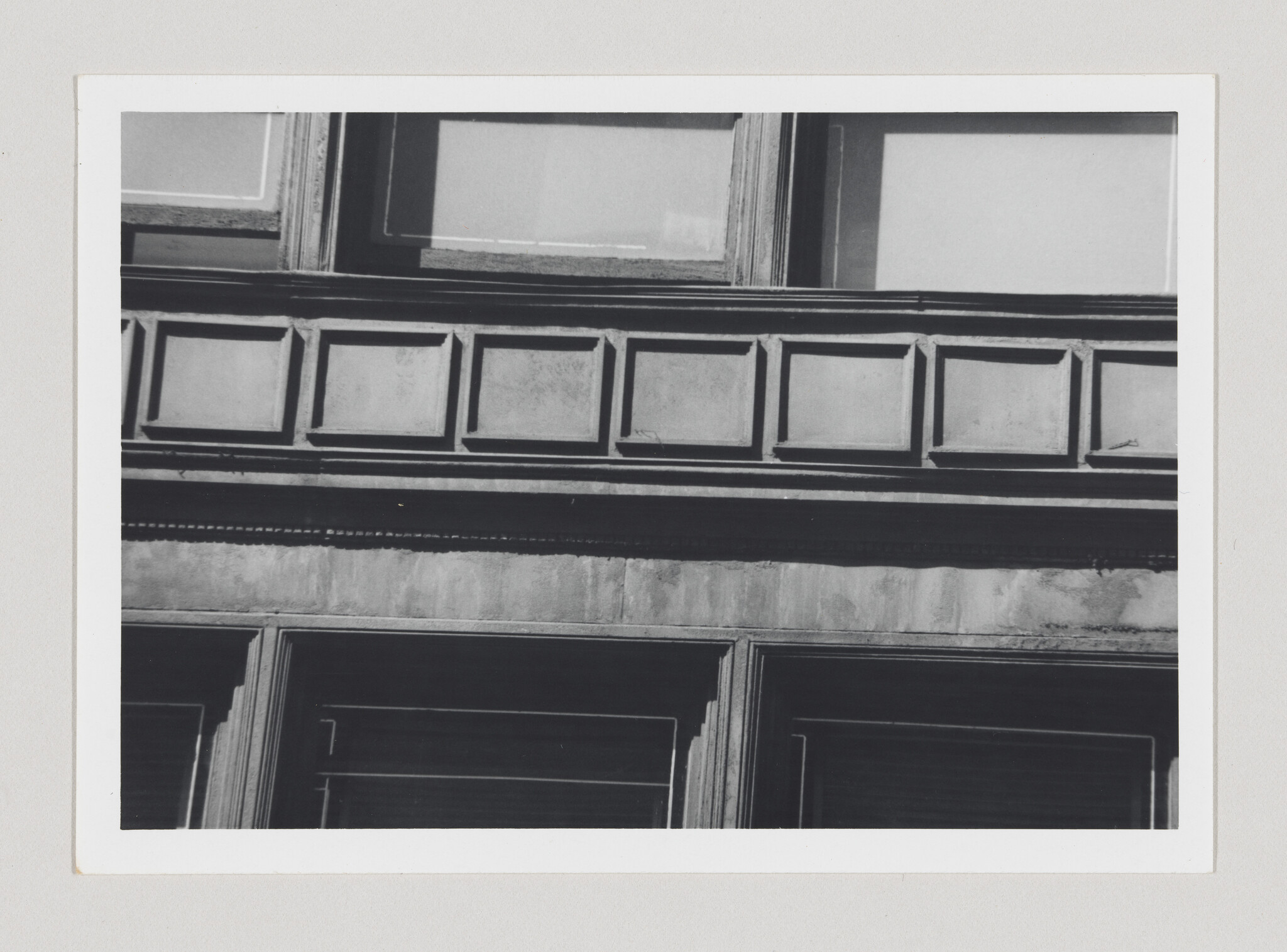 Close-up of a building facade showing rectangular decorative panels and window frames.