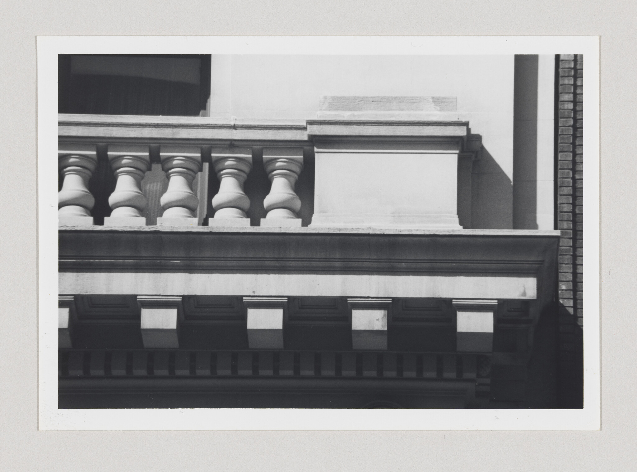 Stone balustrade and decorative cornice on a classical building facade in sunlight.
