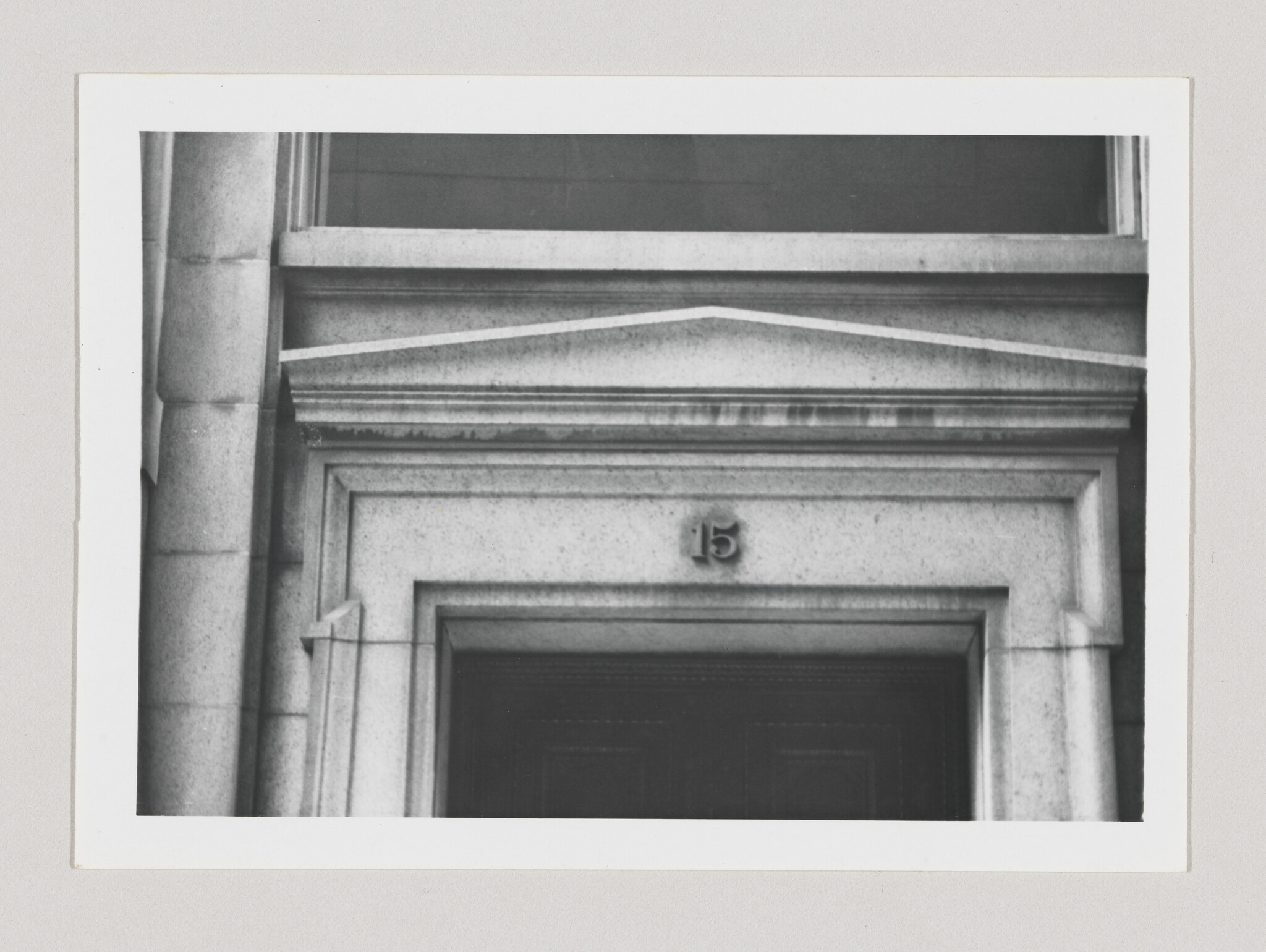Stone building entrance with decorative pediment and the number 15 above the doorway.
