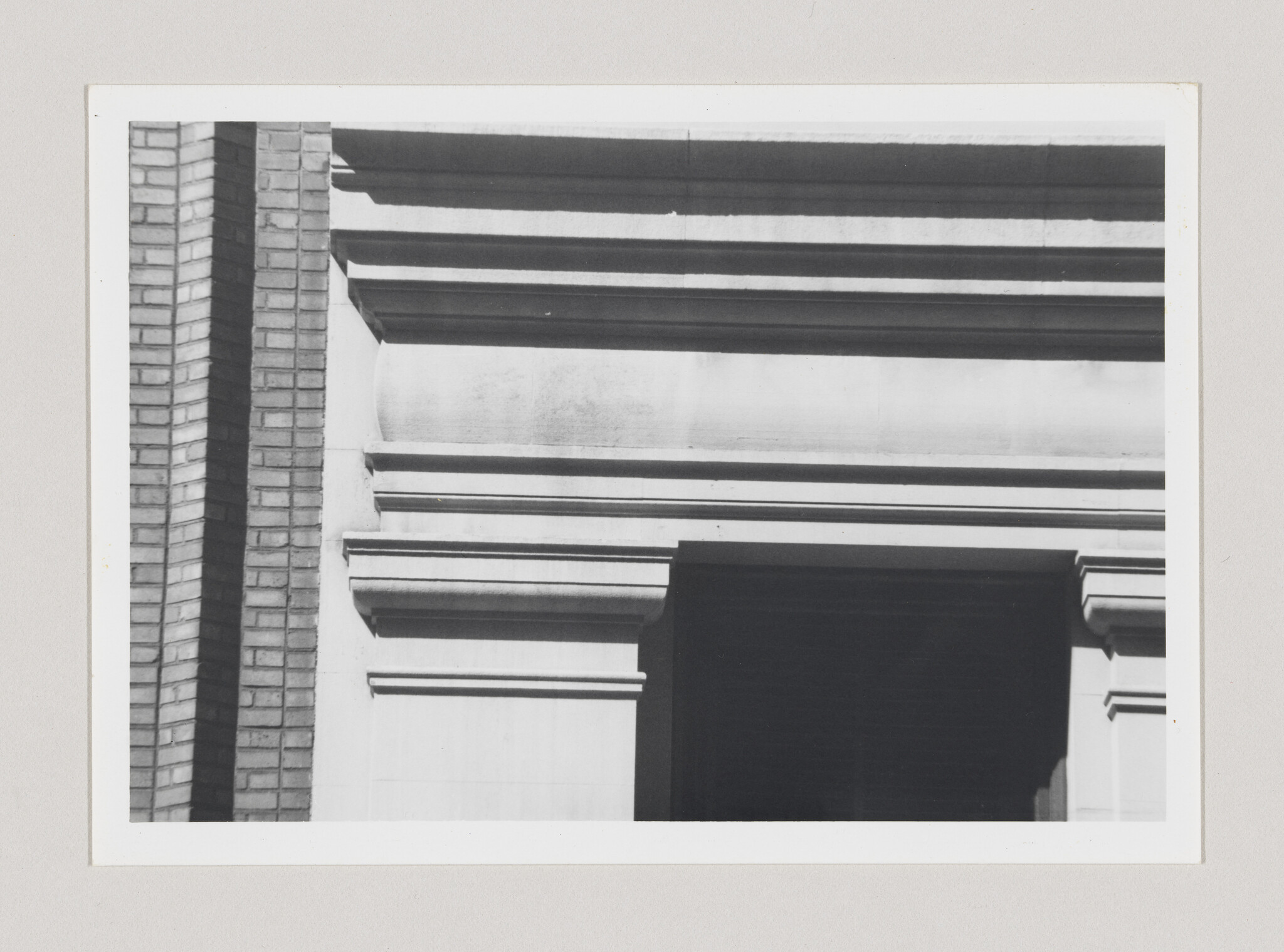 Stone building facade with layered cornices, a recessed dark doorway, and brick column.