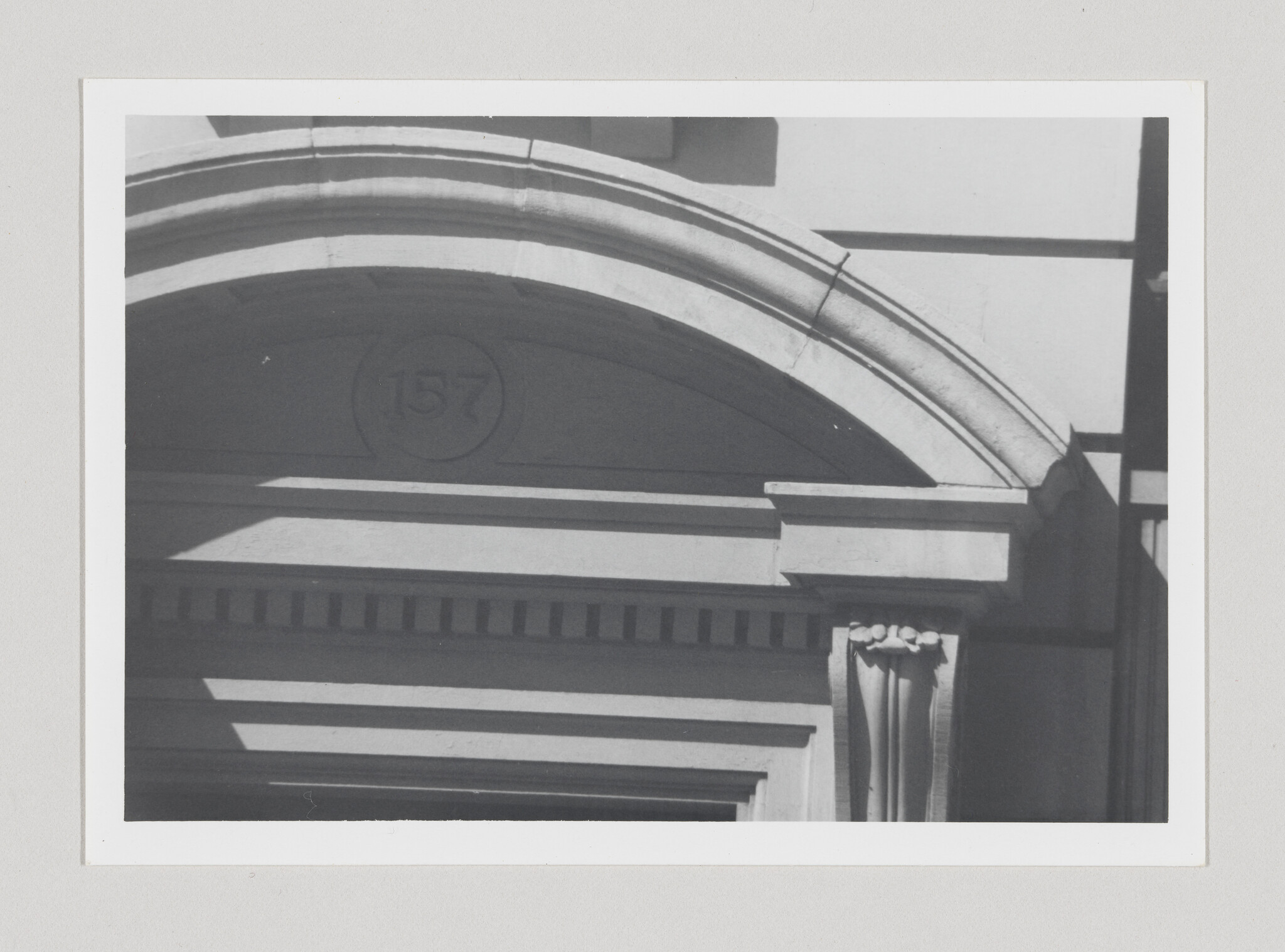 Arched stone entrance with decorative column and number 157 above the doorway.