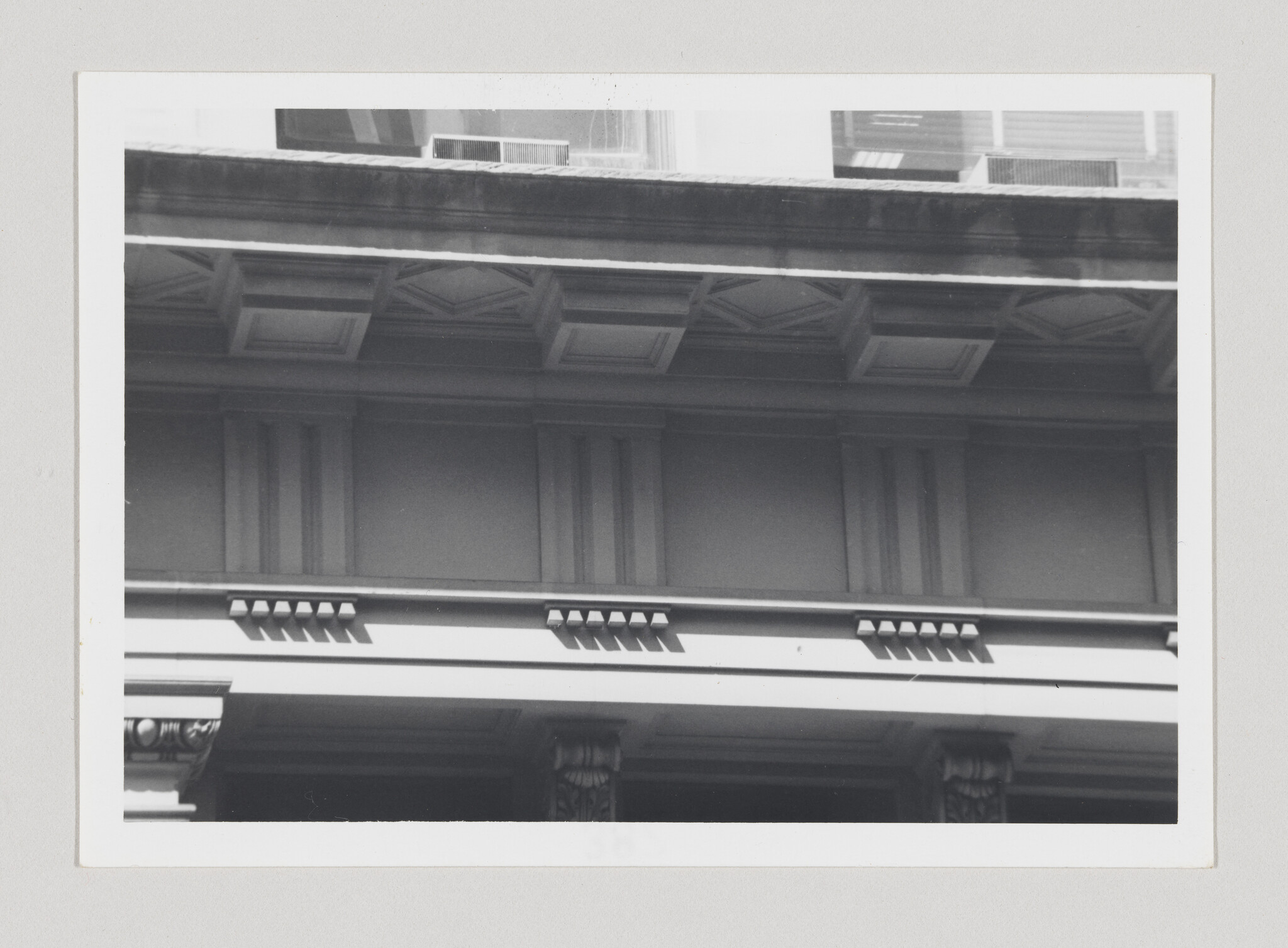 Ornate classical building cornice and decorative columns with dentil molding and recessed panels.